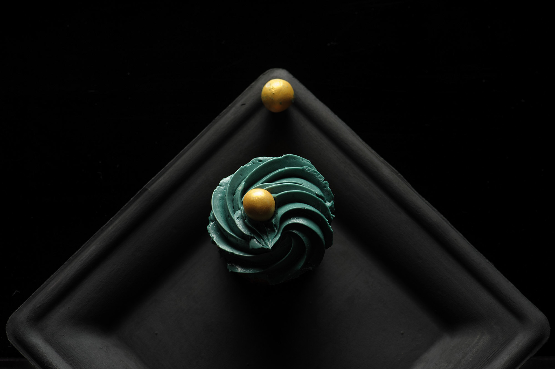 Μινιμαλιστική φωτογραφία γλυκού cupcake με σκούρο φόντο και έντονη αντίθεση φωτός.    Minimal still life of a cupcake on a dark background with dramatic lighting contrast.