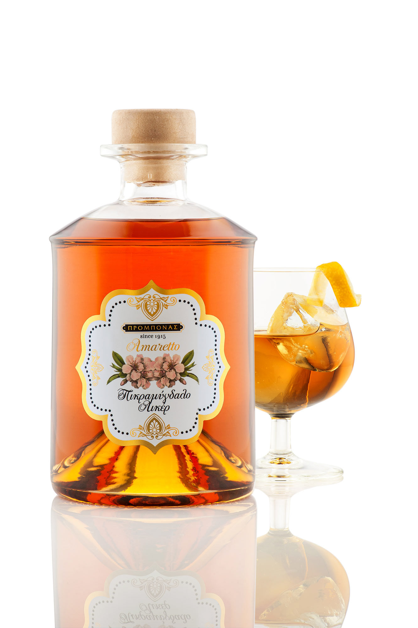 προιοντική φωτογραφία μπουκαλιού amaretto με ποτήρι δίπλα γεμάτο σε λευκό φόντο με αντανάκλαση