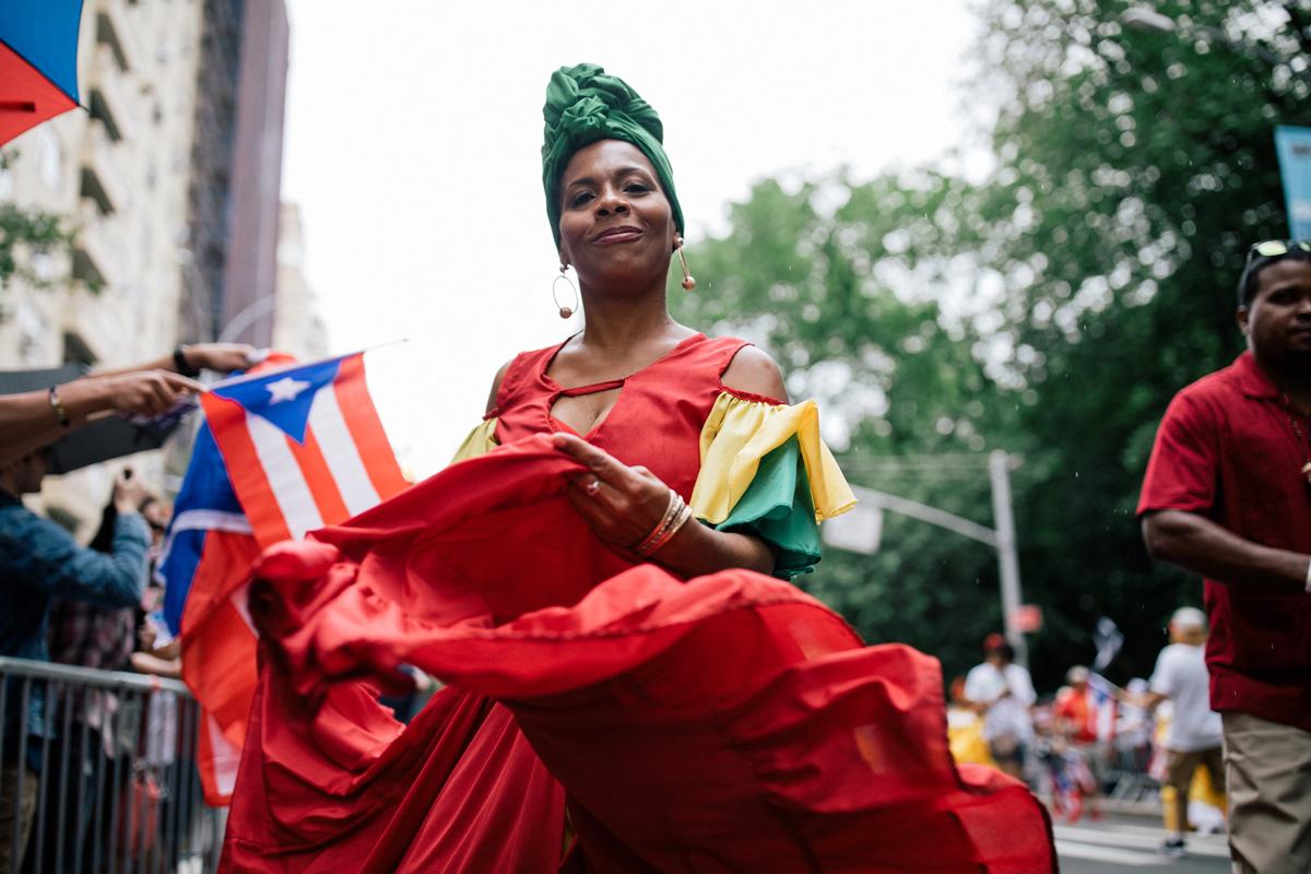 A woman in a traditional “bomba y plena” dress performs folk dances at Fifth Avenue and 75th Street.