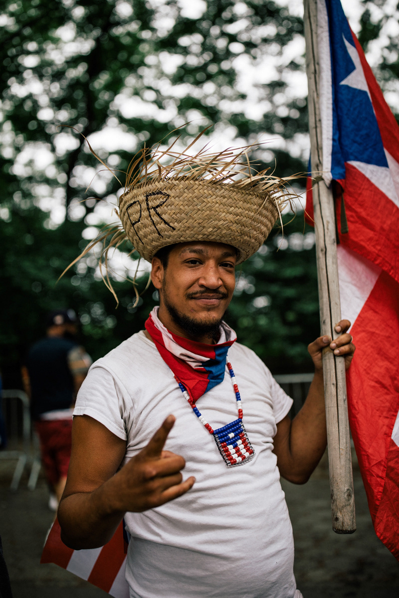 A member of the crowd holds a Puerto Rican flag and traditional Jibaro hat at Fifth Avenue and 76th Street.