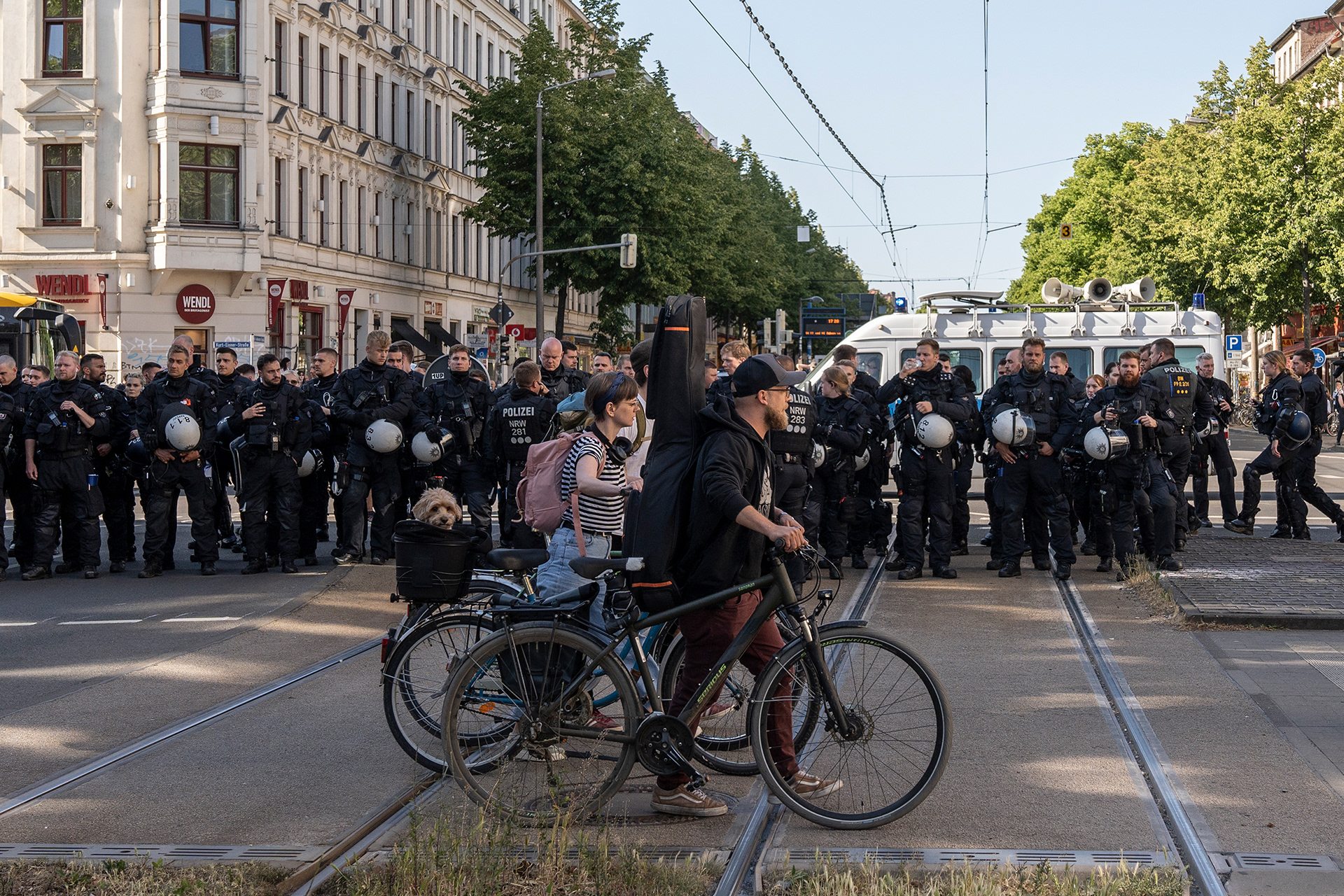 Fußgänger laufen an Polizist*innen vorbei.