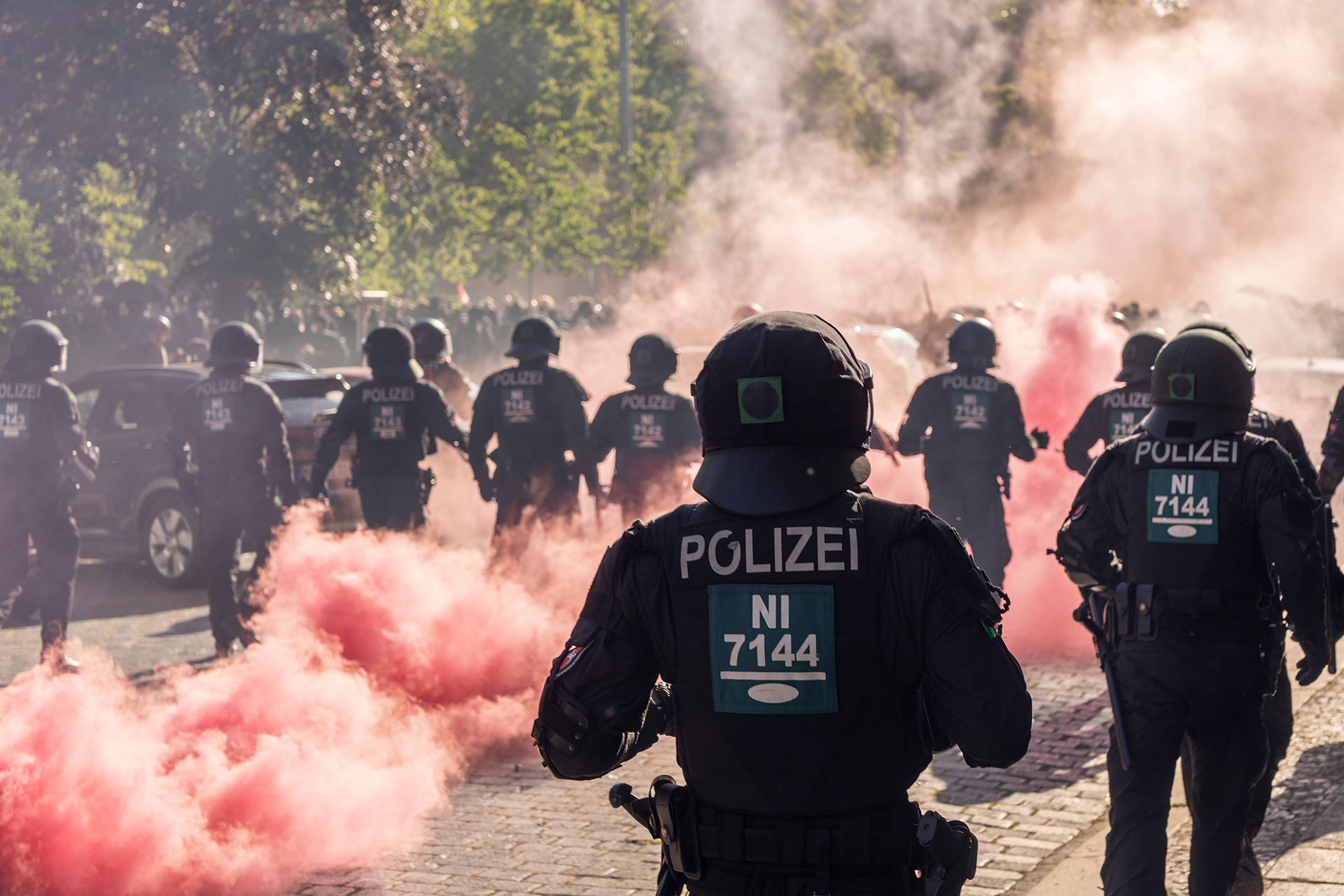 Polizist*innen stehen im Rauch von Pyrotechnik.