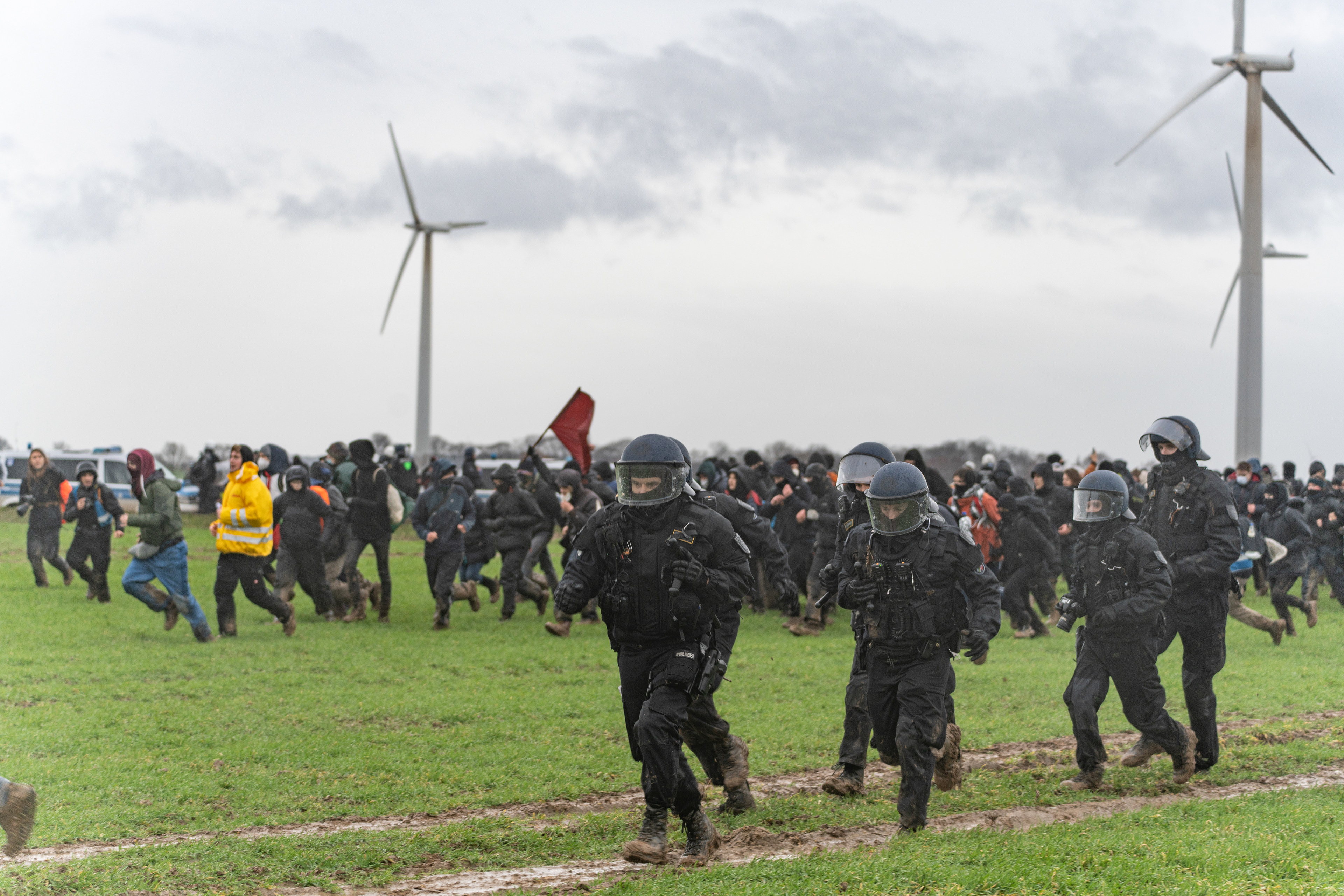 Demonstrant*innen durchbrechen die Polizeikette und rennen neben den Beamt*innen in Richtung Lützerath