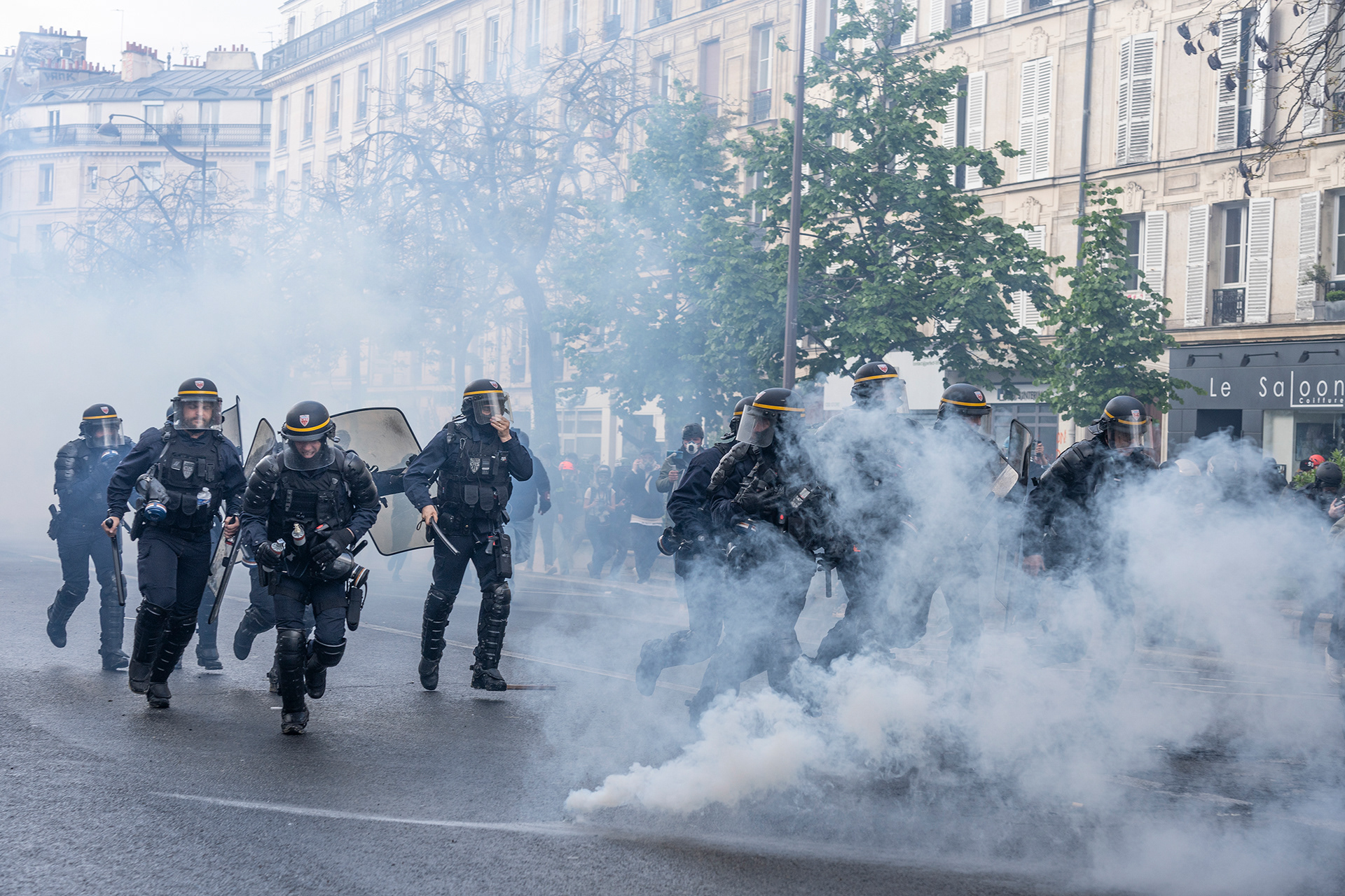 Polizist*innen rennen durch Wolken aus Tränengas.