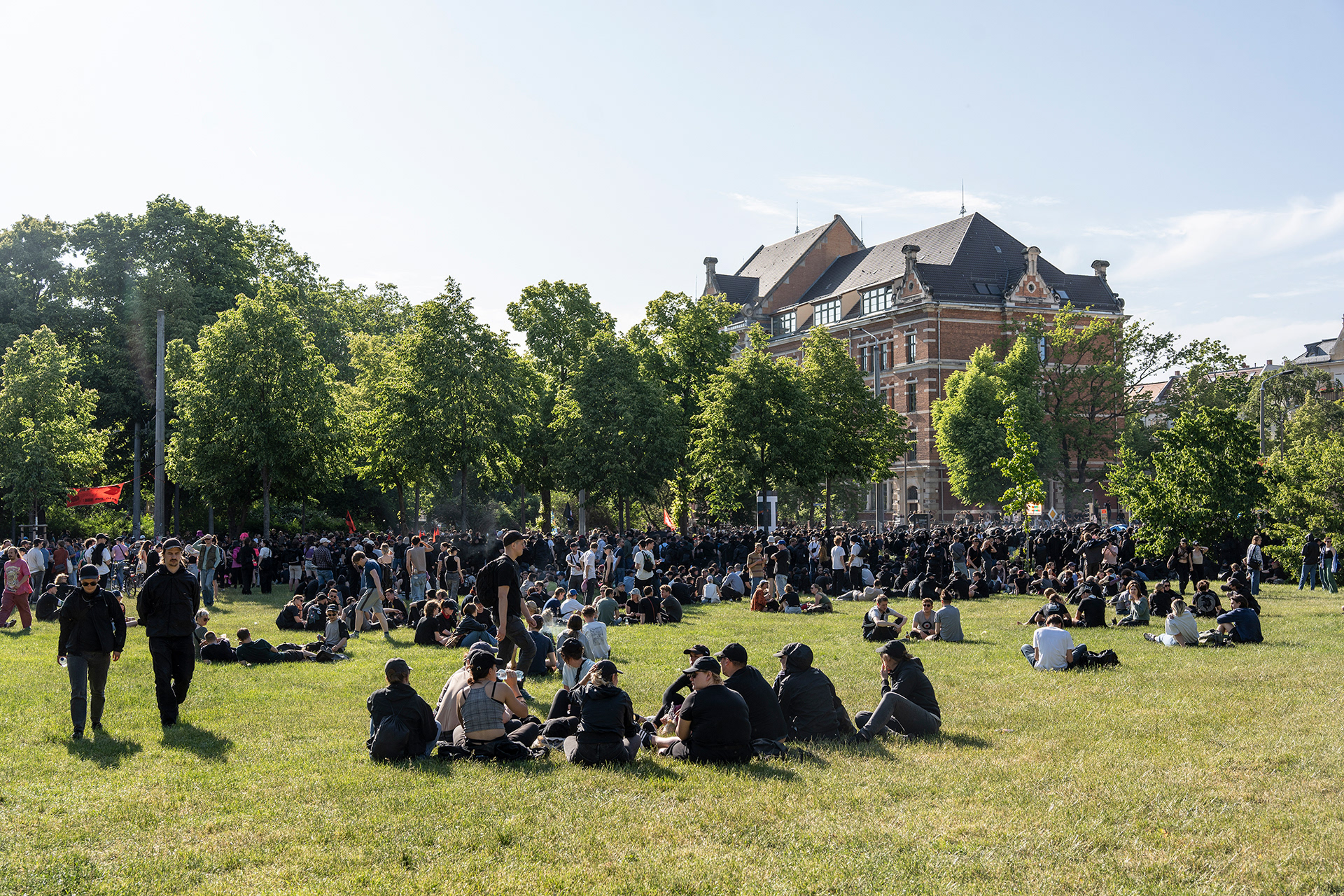 Demonstrationsteilnehmer*innen versammeln sich in einem Park.