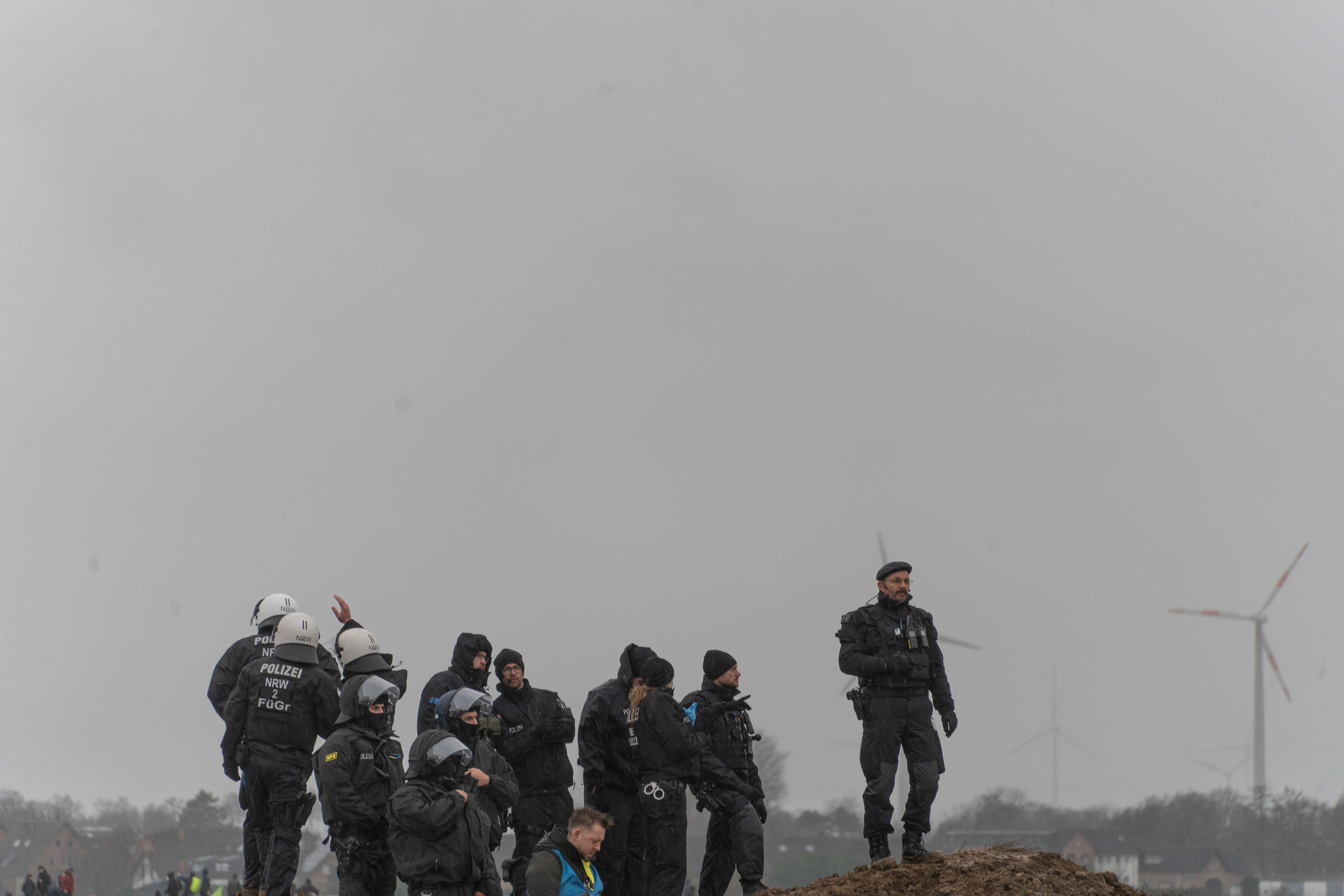 Ein Ranghöherer Polizist sieht sich die Situation von einem Hügel aus an