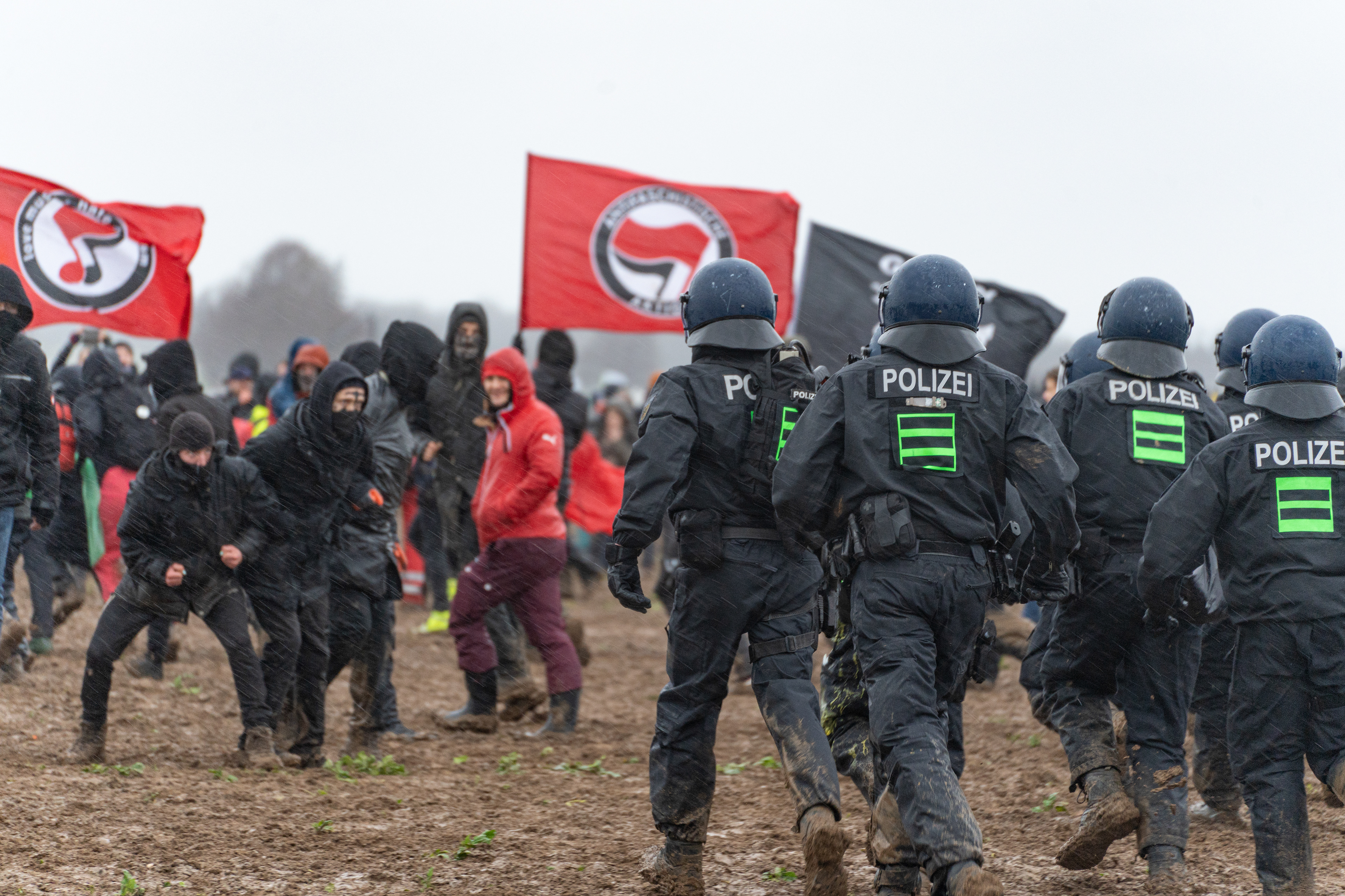 Polizist*innen maschieren auf eine Gruppe Demonstrant*innen zu