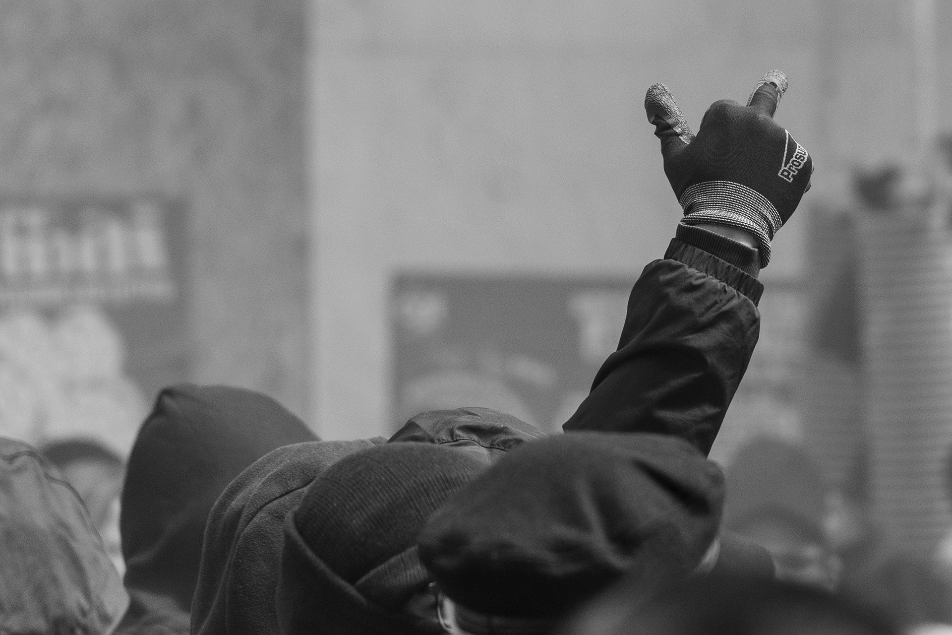 Erhobener Mittefinger aus der Masse der Demonstrant*innen