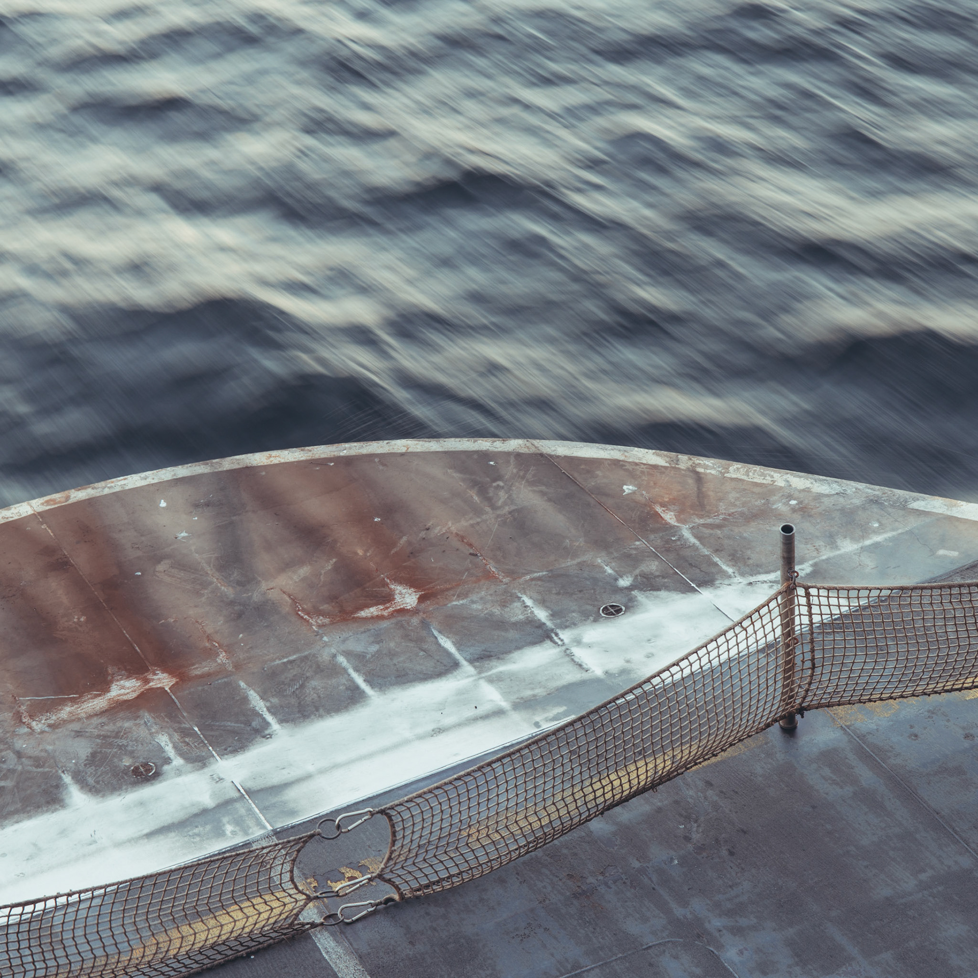A crescent of weather-worn deck and safety net slices into the blurred waters of Puget Sound as the Seattle–Bainbridge ferry glides between city and island.