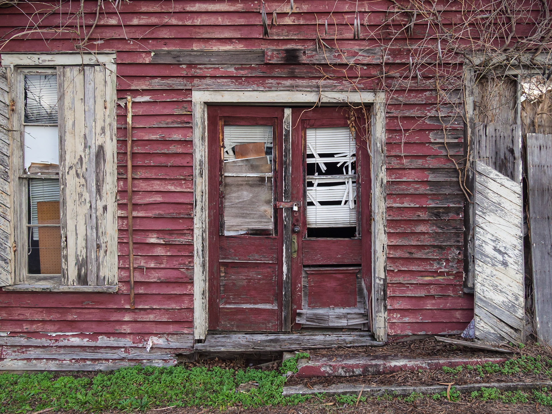 Doors, windows and vines on a deteriorating red wooden building in Woodbury, Georgia, in December 2015