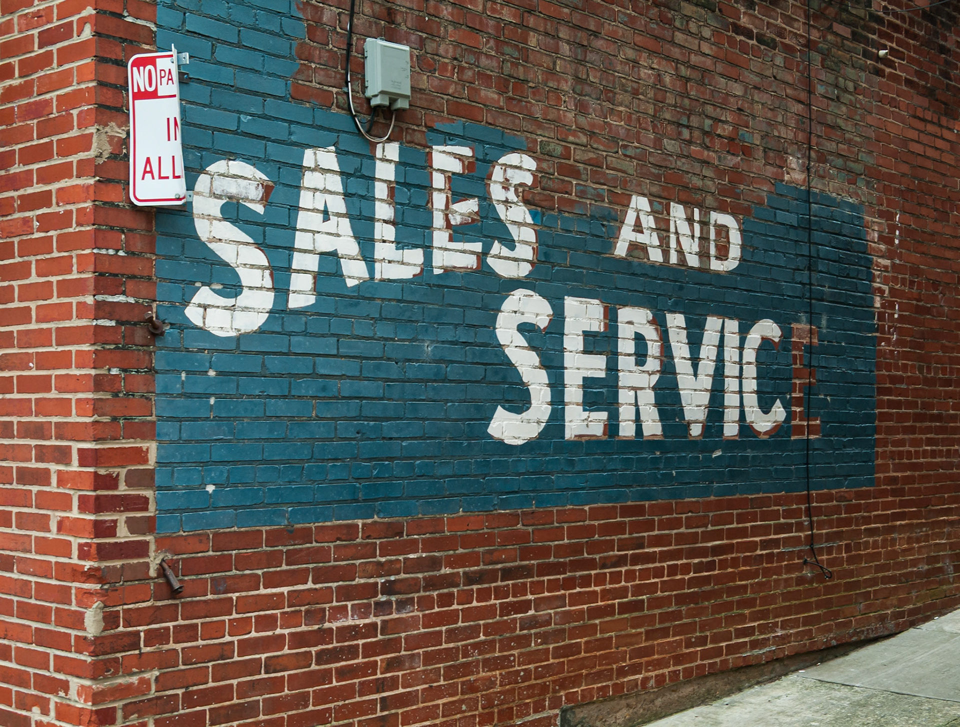 A faded painted “Sales and Service” sign on a brick wall in downtown Canton, Georgia, photographed in May 2014
