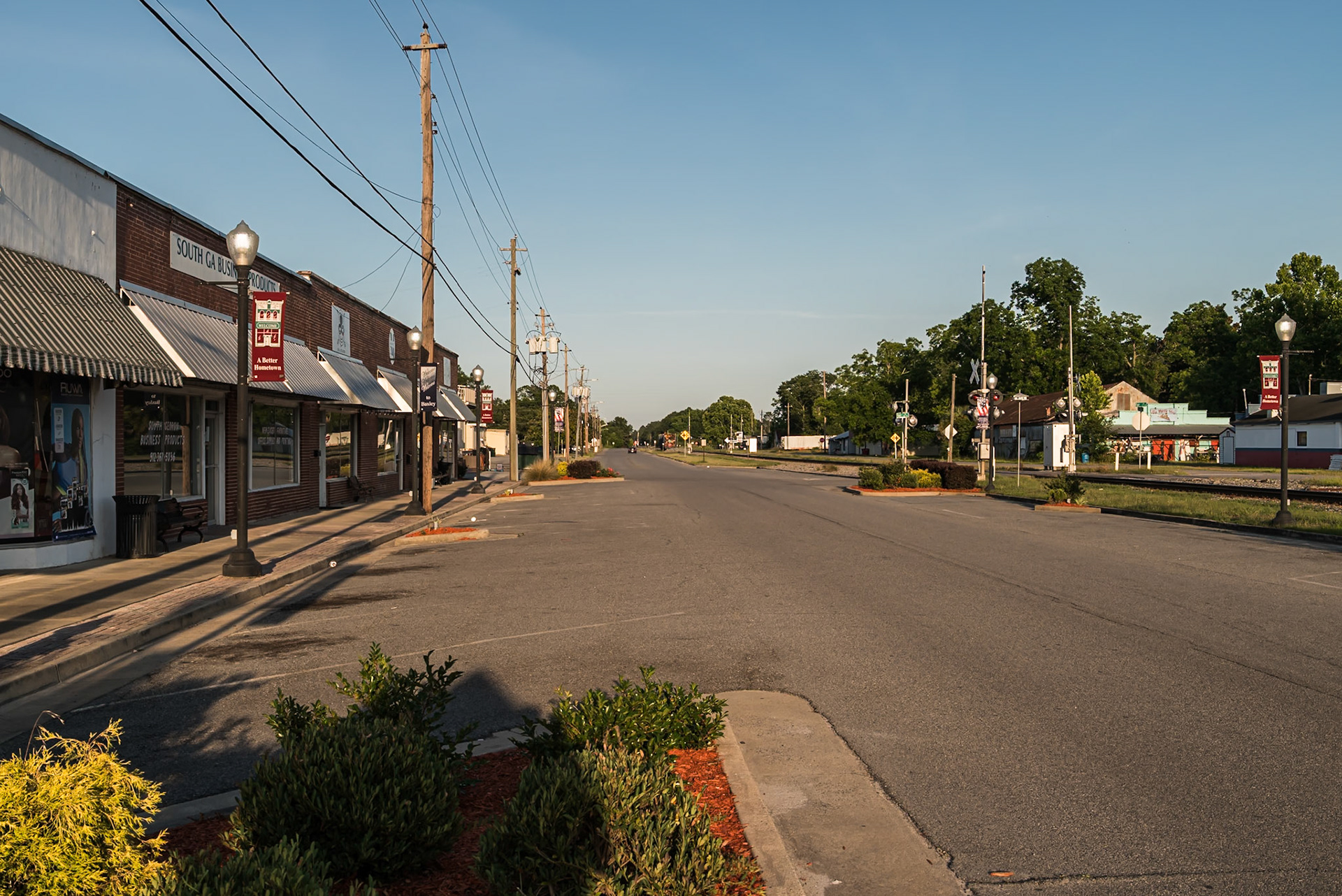 Commercial buildings and the railroad corridor through downtown Baxley, in June 2024
