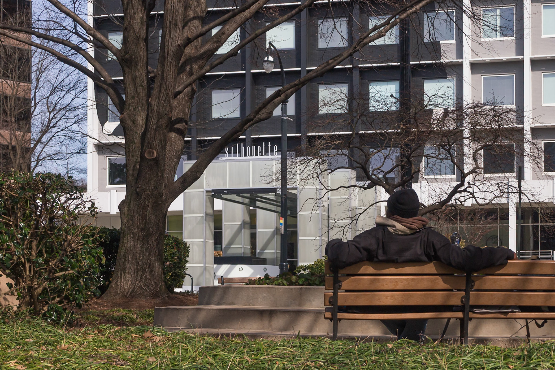 A man sits on a bench outside Silhouette Midtown on Peachtree Street.