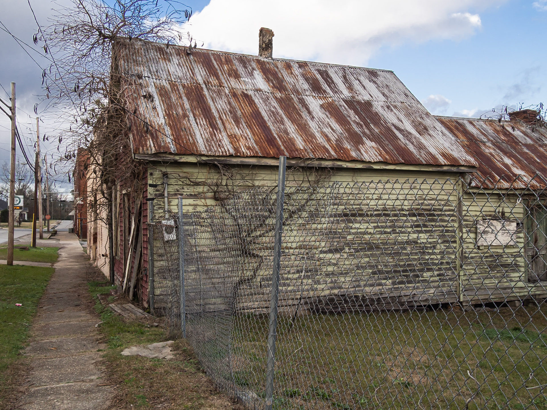 A weathered green outbuilding with an old metal roof and chimney in Woodbury, Georgia, in December 2015