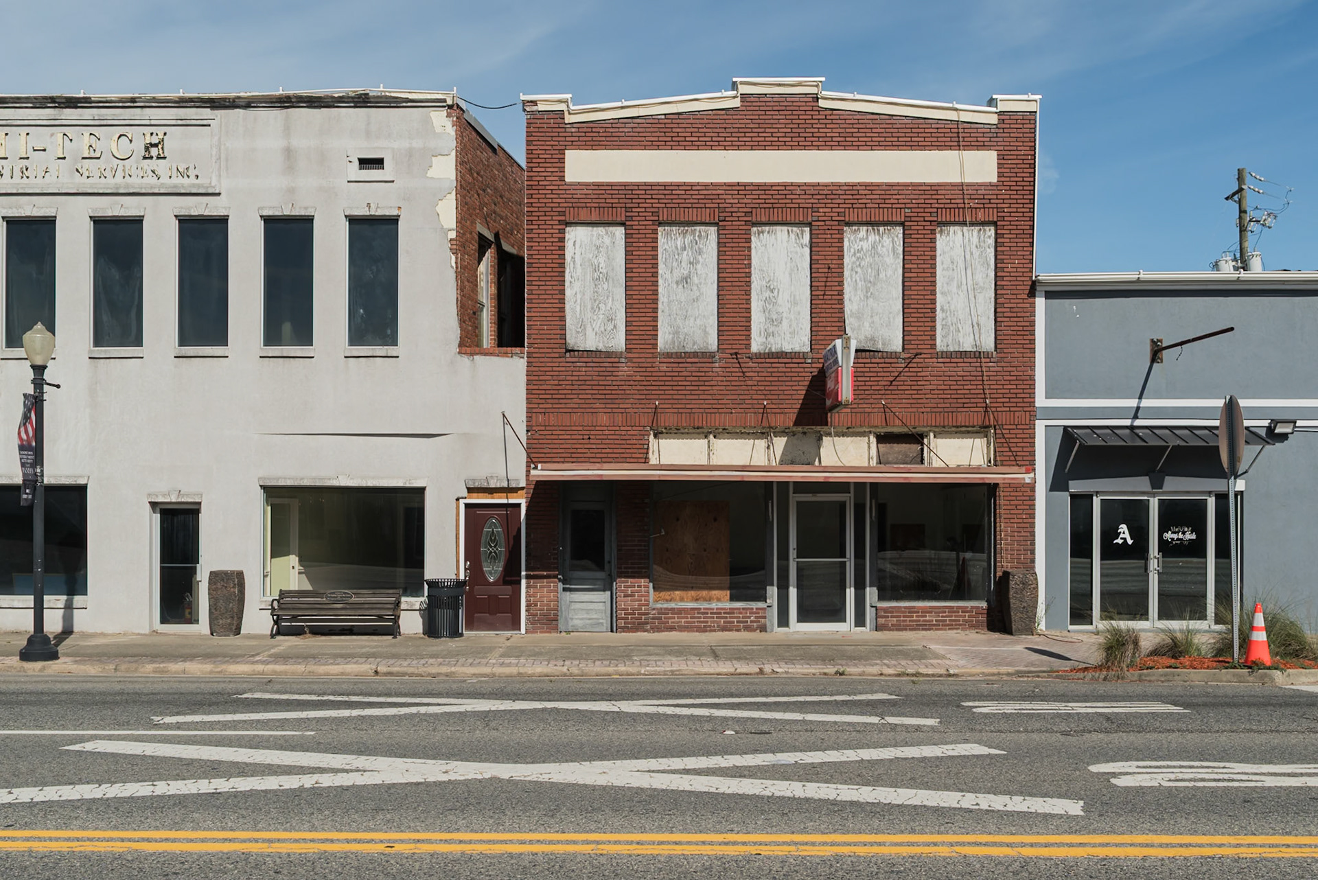 A weathered brick commercial building with boarded upper windows in downtown Baxley, in June 2024
