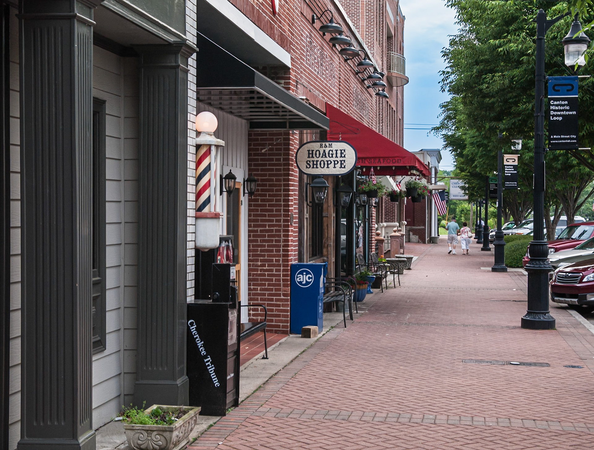 A brick sidewalk lined with shops and historic-district street furniture in downtown Canton, Georgia, photographed in May 2014