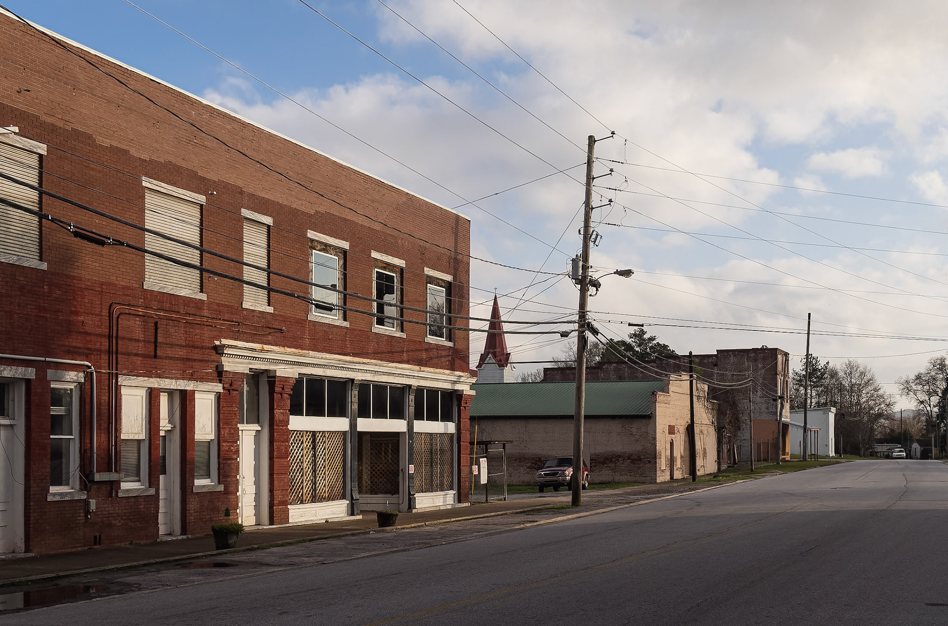 A long red brick commercial building along a street in downtown Woodbury, Georgia, in December 2015