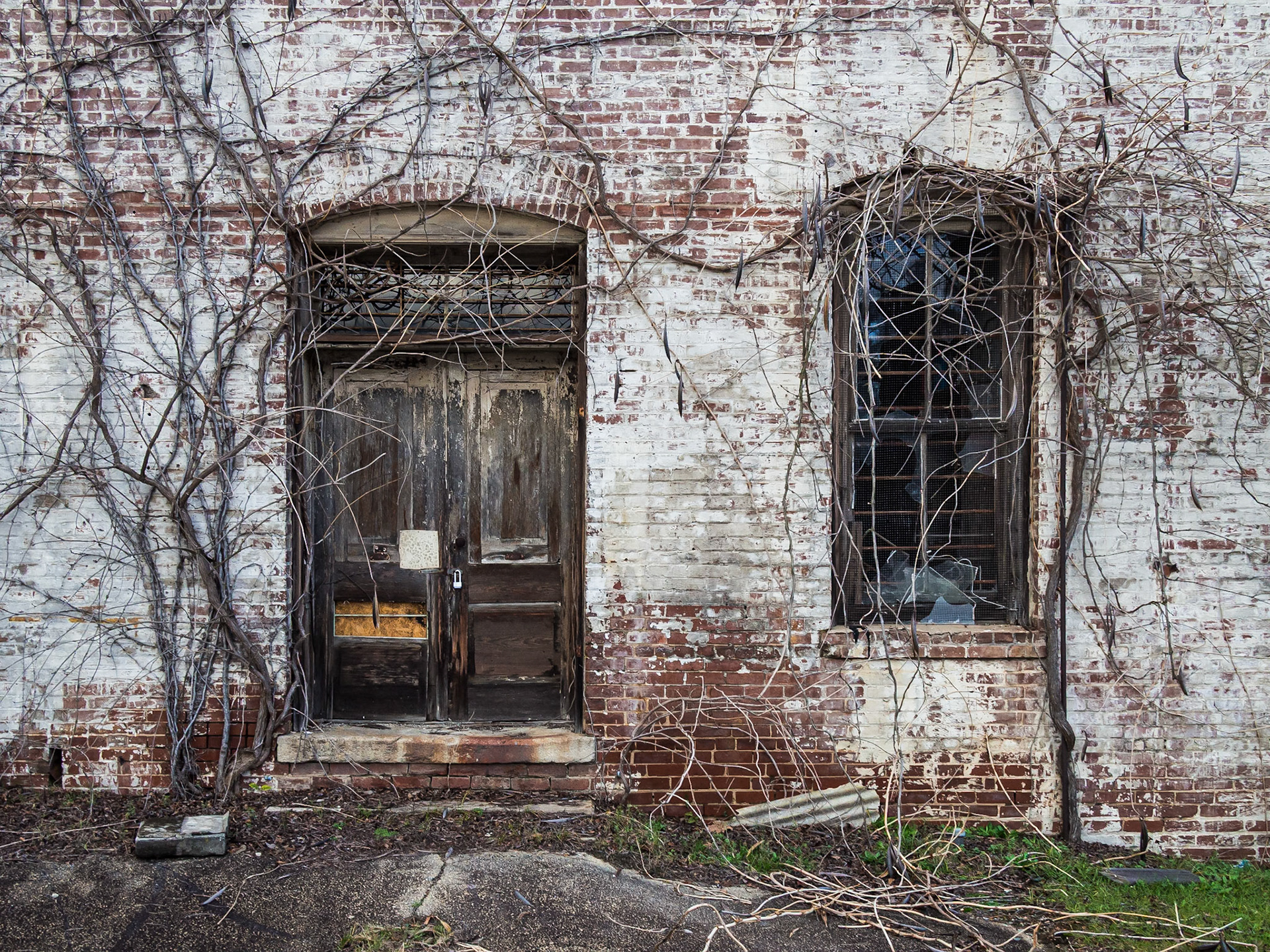 oarded openings and vines on a deteriorating brick building in Woodbury, Georgia, in December 2015