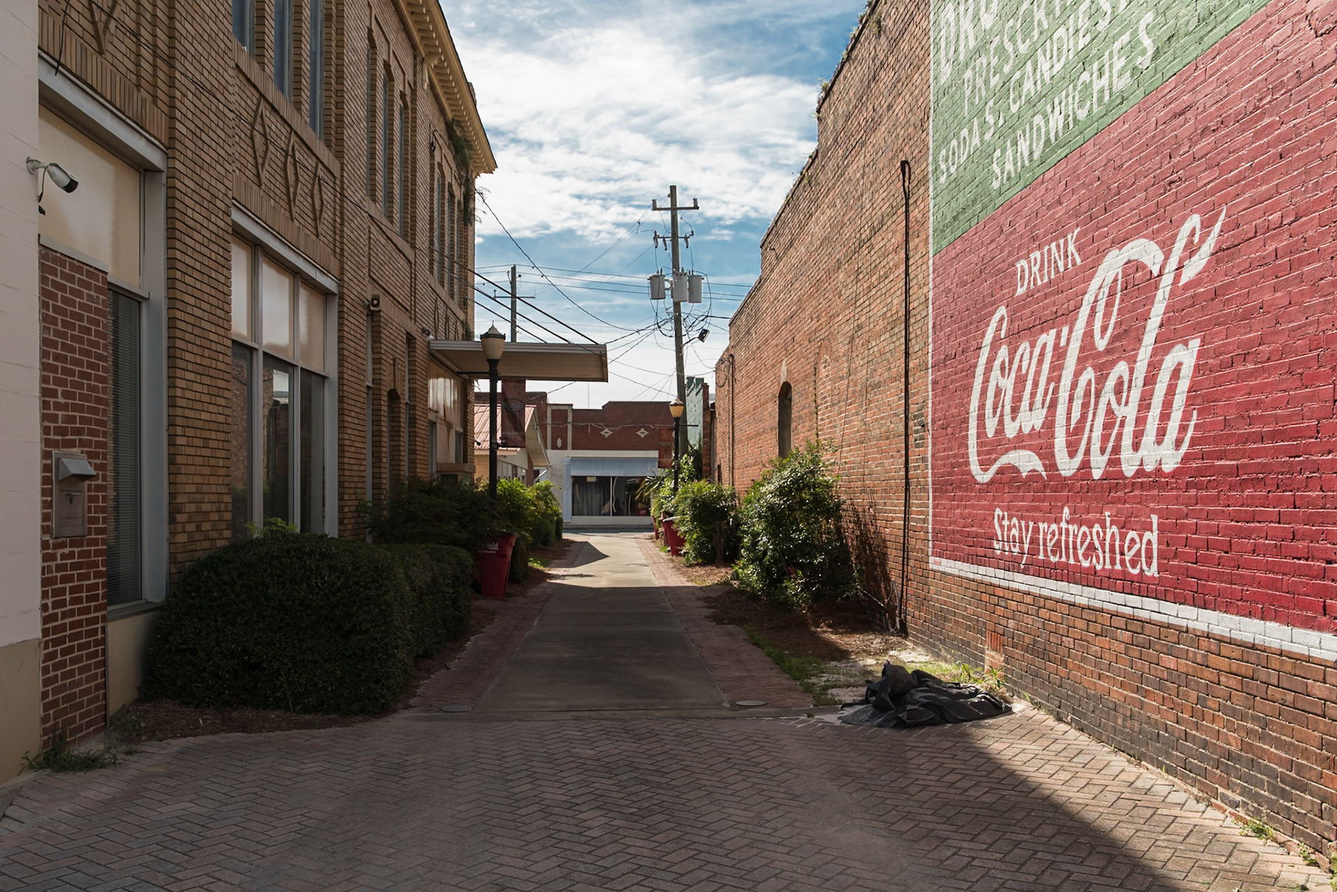 A painted Coca-Cola advertisement on a brick wall along a downtown passageway in Baxley, in June 2024