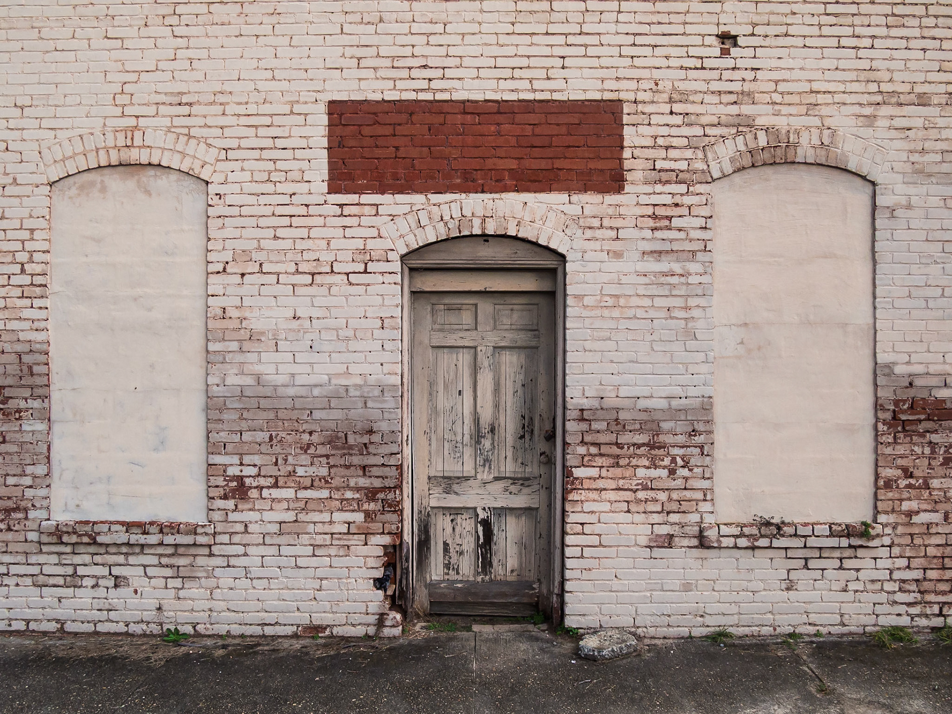 A painted brick facade with arched openings and a weathered wooden door in Woodbury, Georgia, in December 2015