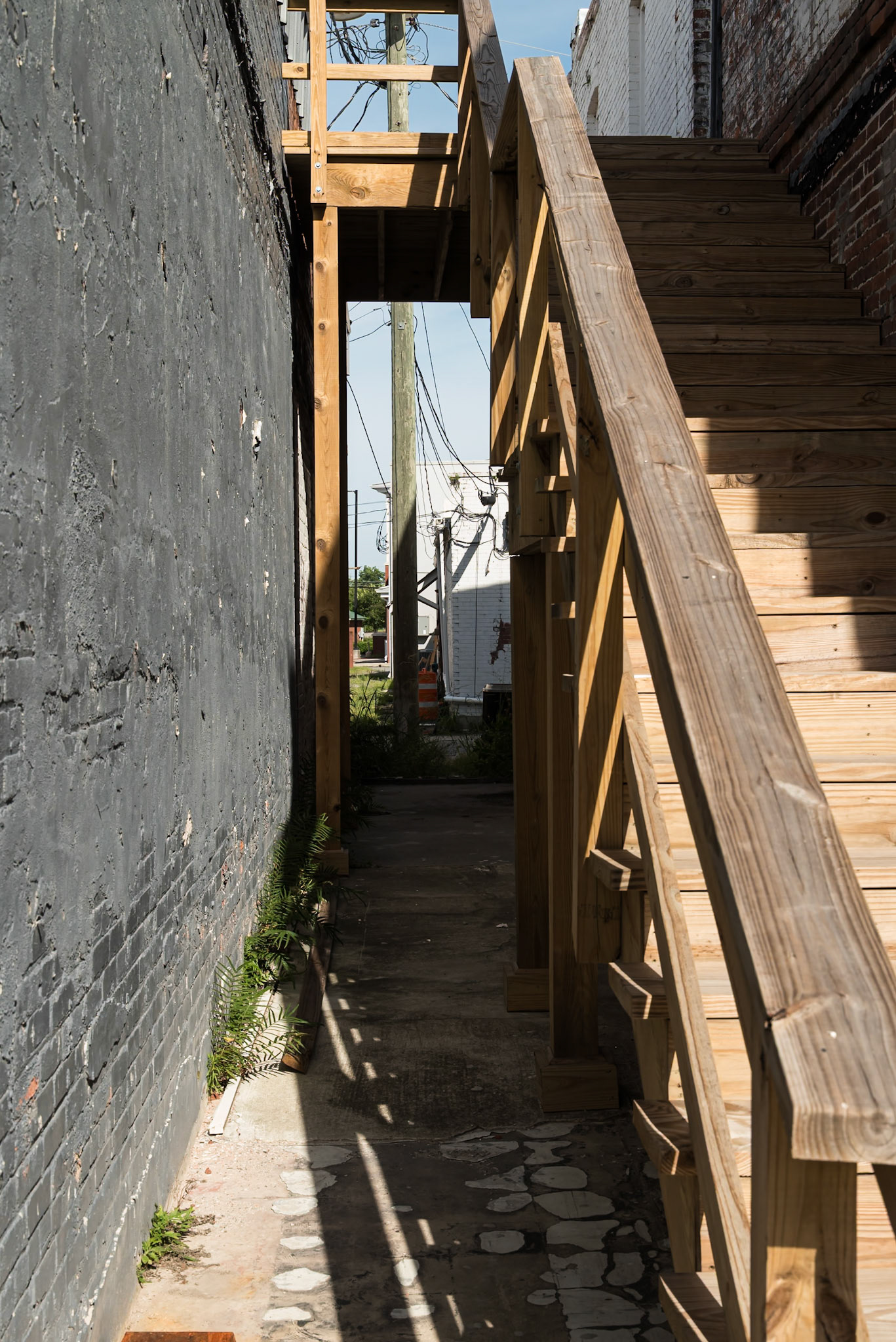 wooden exterior stairway in a narrow passage between downtown commercial buildings in Baxley, in June 2024