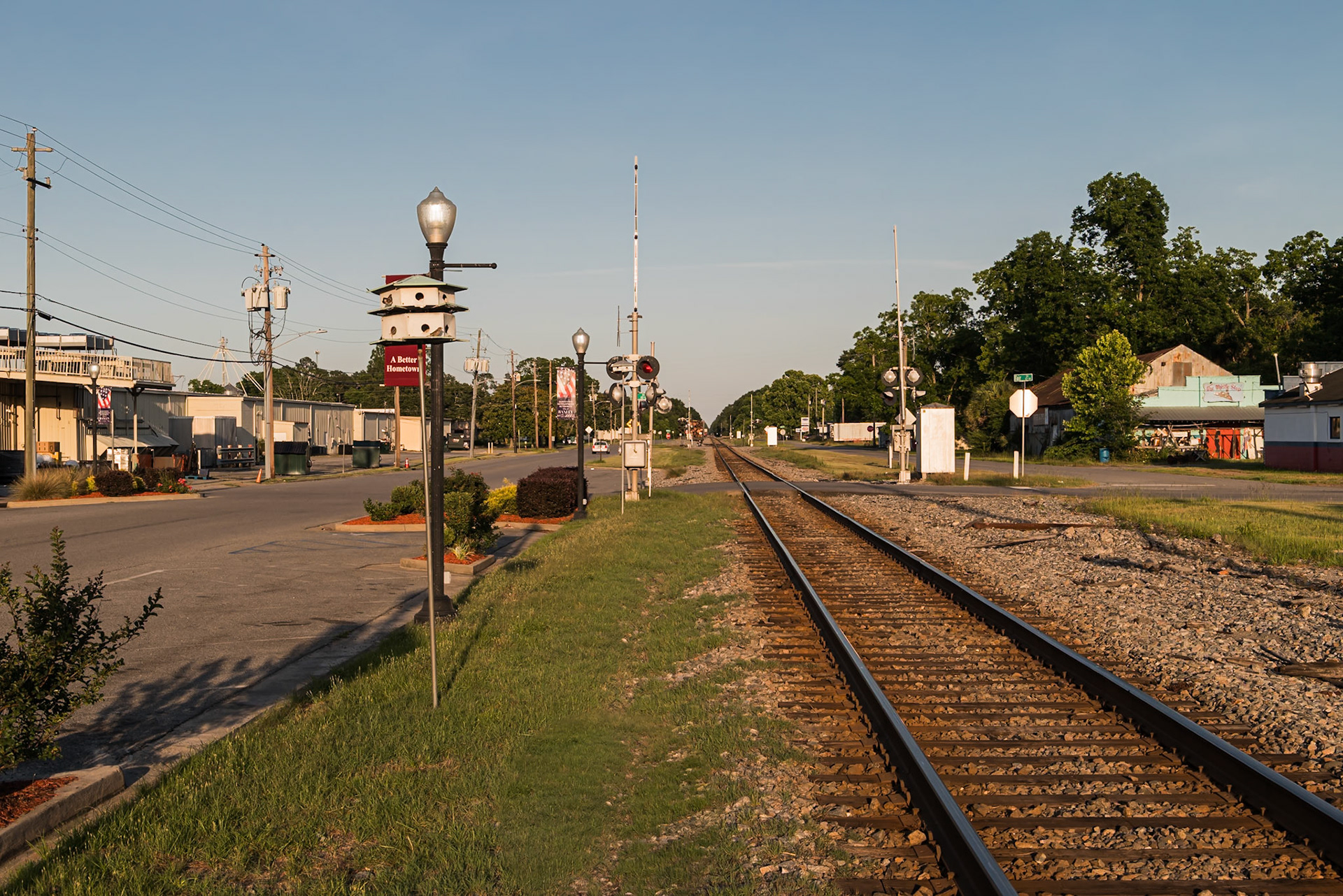 Railroad tracks extending through Baxley beside downtown streets and commercial buildings, in June 2024
