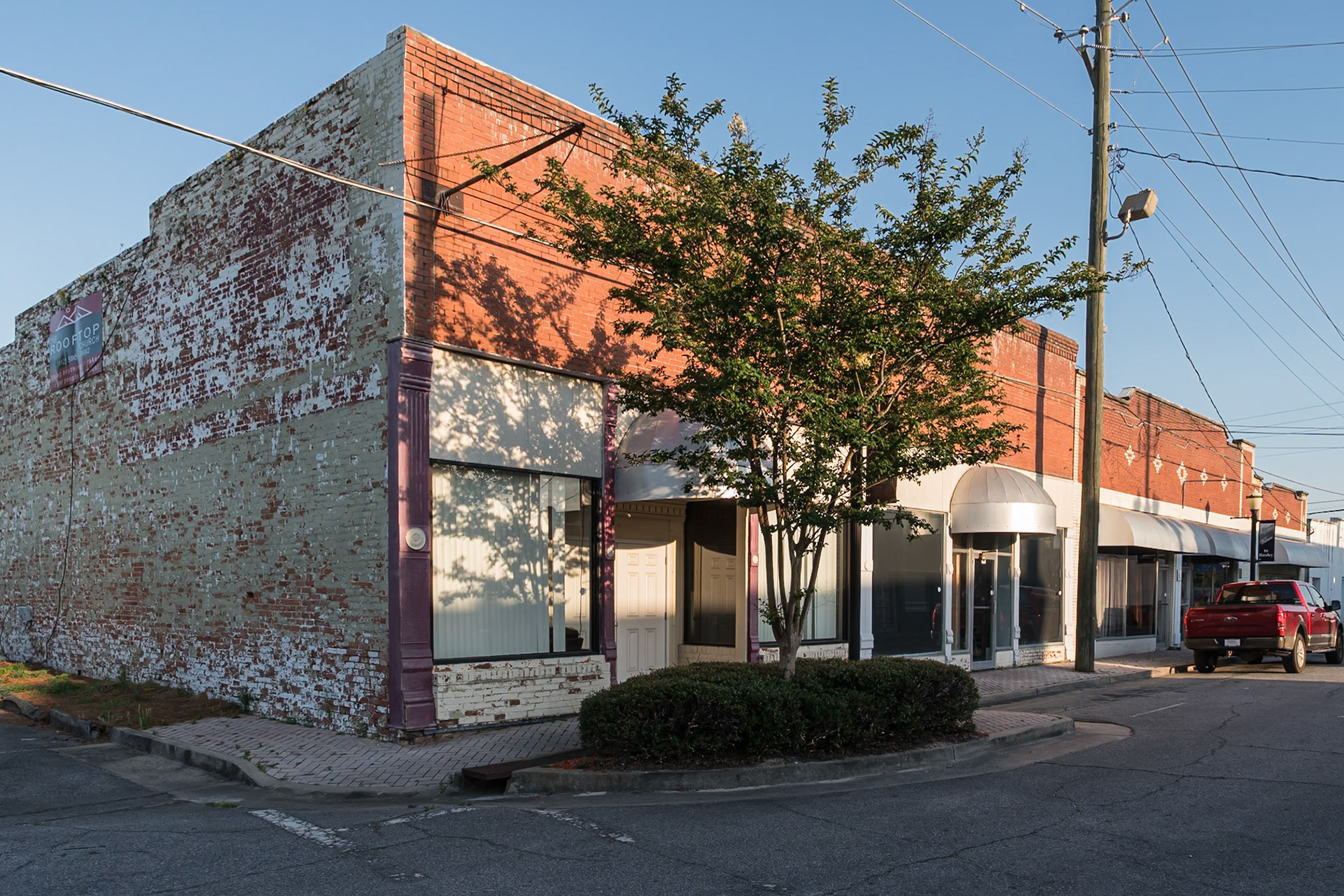 Older commercial storefronts along a side street in downtown Baxley., in June 2024