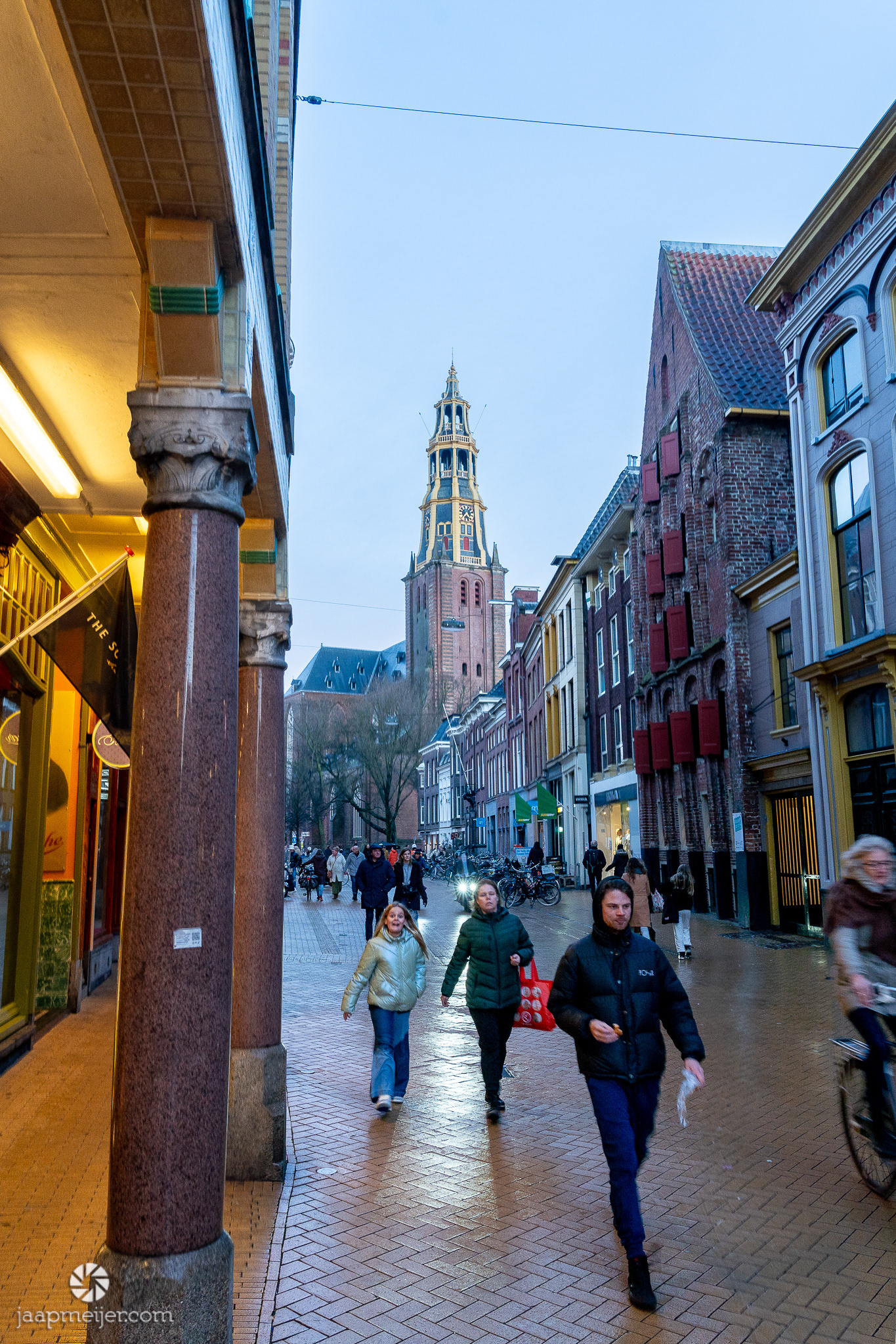 Mensen doen nog even de laatste boodschapjes. De straten glimmen nog van de regen.