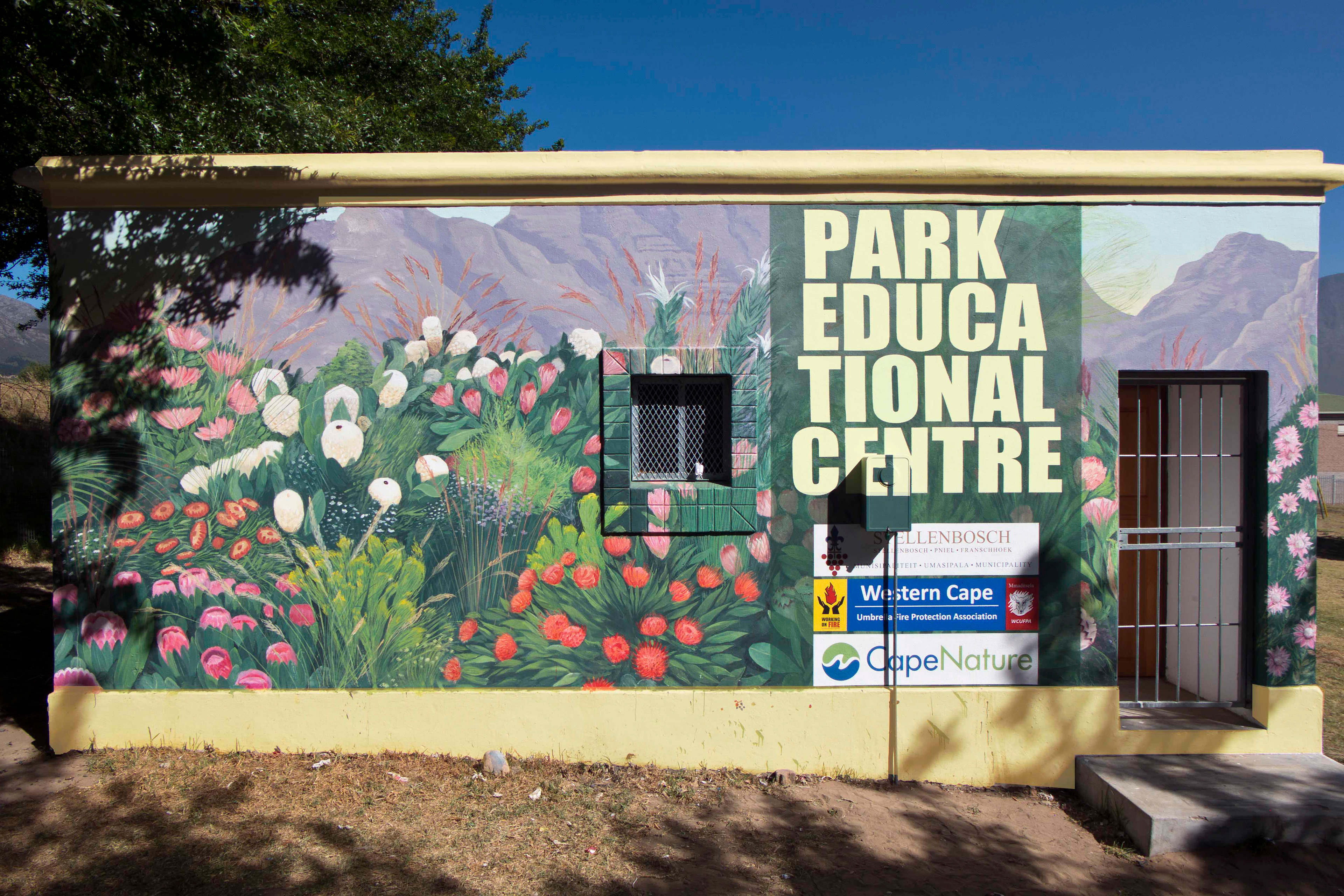 PEC, mural and logos commisioned by the Municipality of Stellenbosch with PVA-paint on plaster at Groendal, Franschhoek, South-Africa.