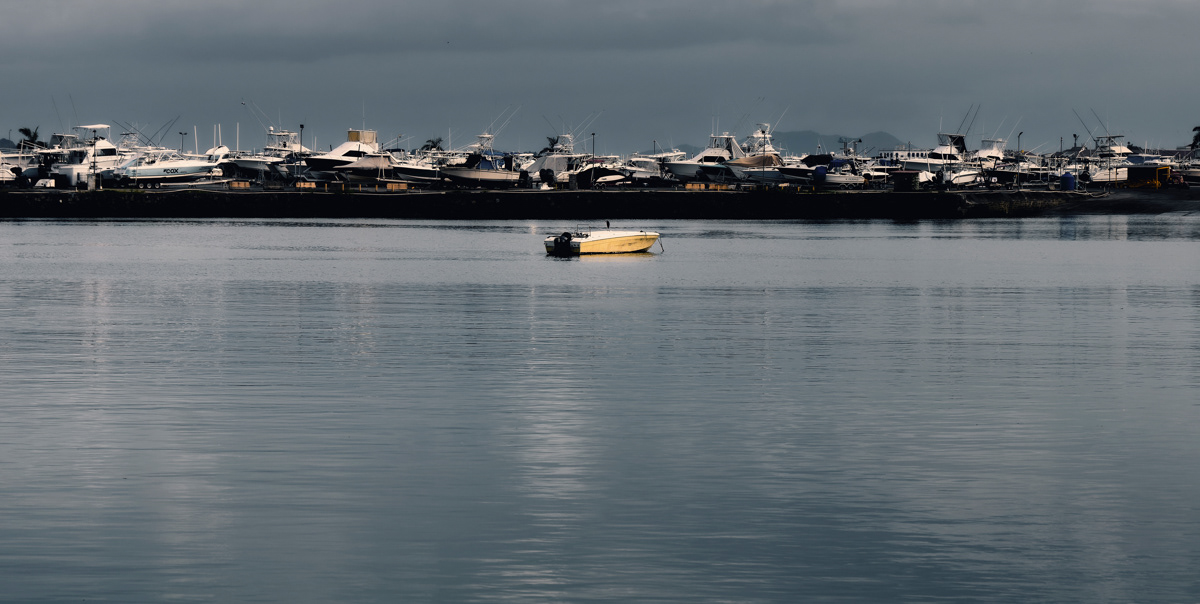 A single lonely boat with a row of boats behind in Panama City