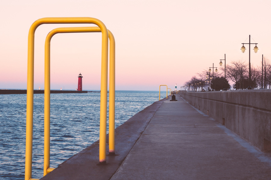 The boardwalk along Lake Michigan and the Kenosha Lighthouse at sunset with the Kenosha North Pier Lighthouse in the distance.