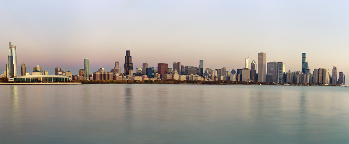 Panoramic photo of Chicago skyline at sunrise overlooking Lake Michigan.