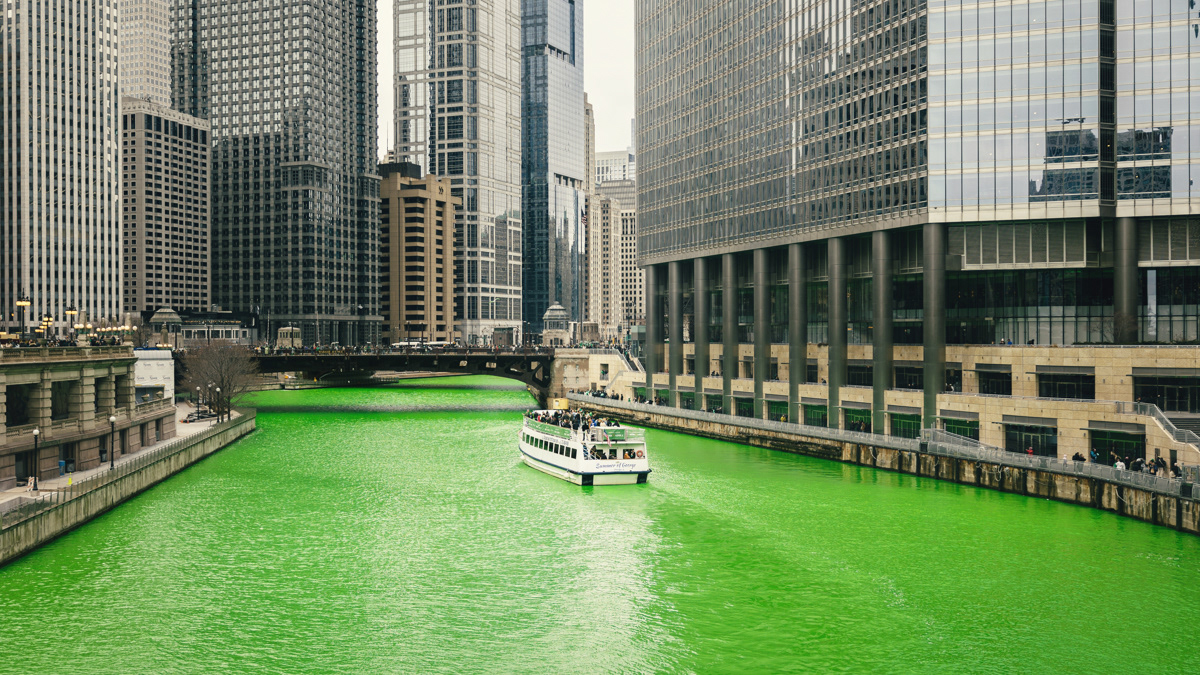 Boat riding down the bright green Chicago River after the river was dyed for St. Patrick's Day.