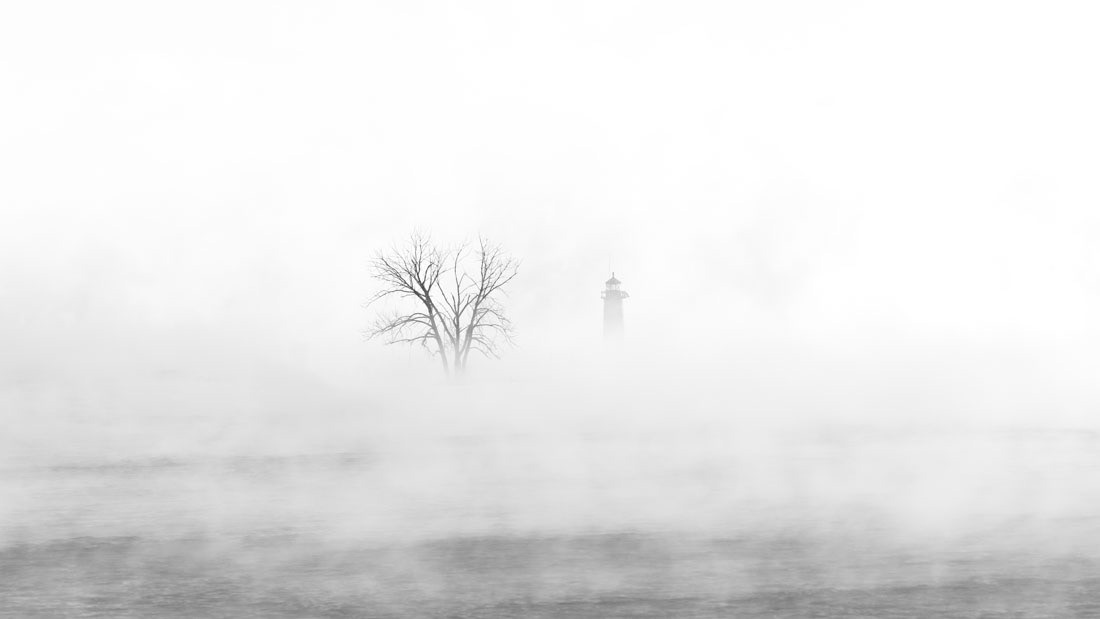 Minimalist photo of tree and Kenosha Pierhead Lighthouse enveloped in fog.