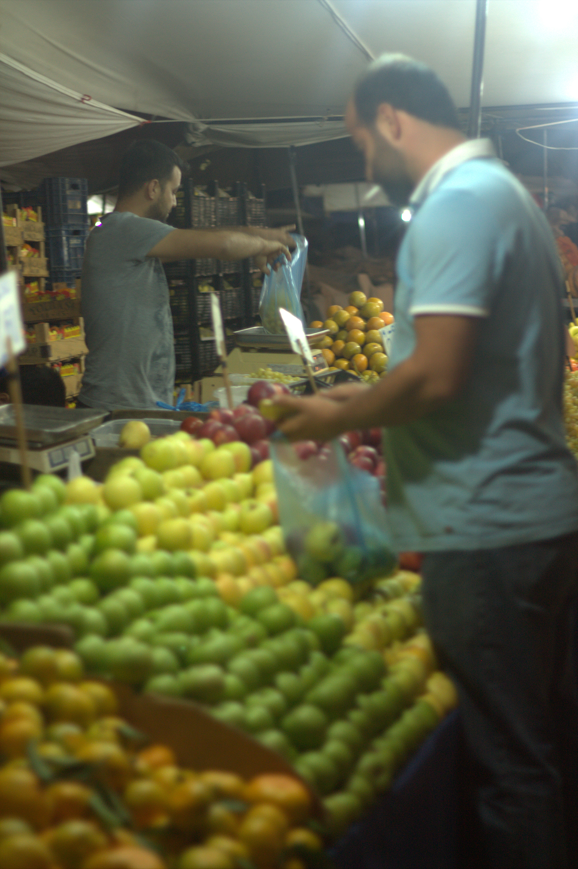 Market vendor bags and weighs a selection of fruit for a customer