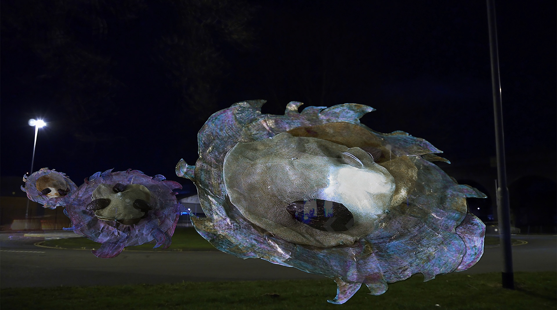 Image description: Three multicolored discs with bronze almond features are shining a bright light at night.