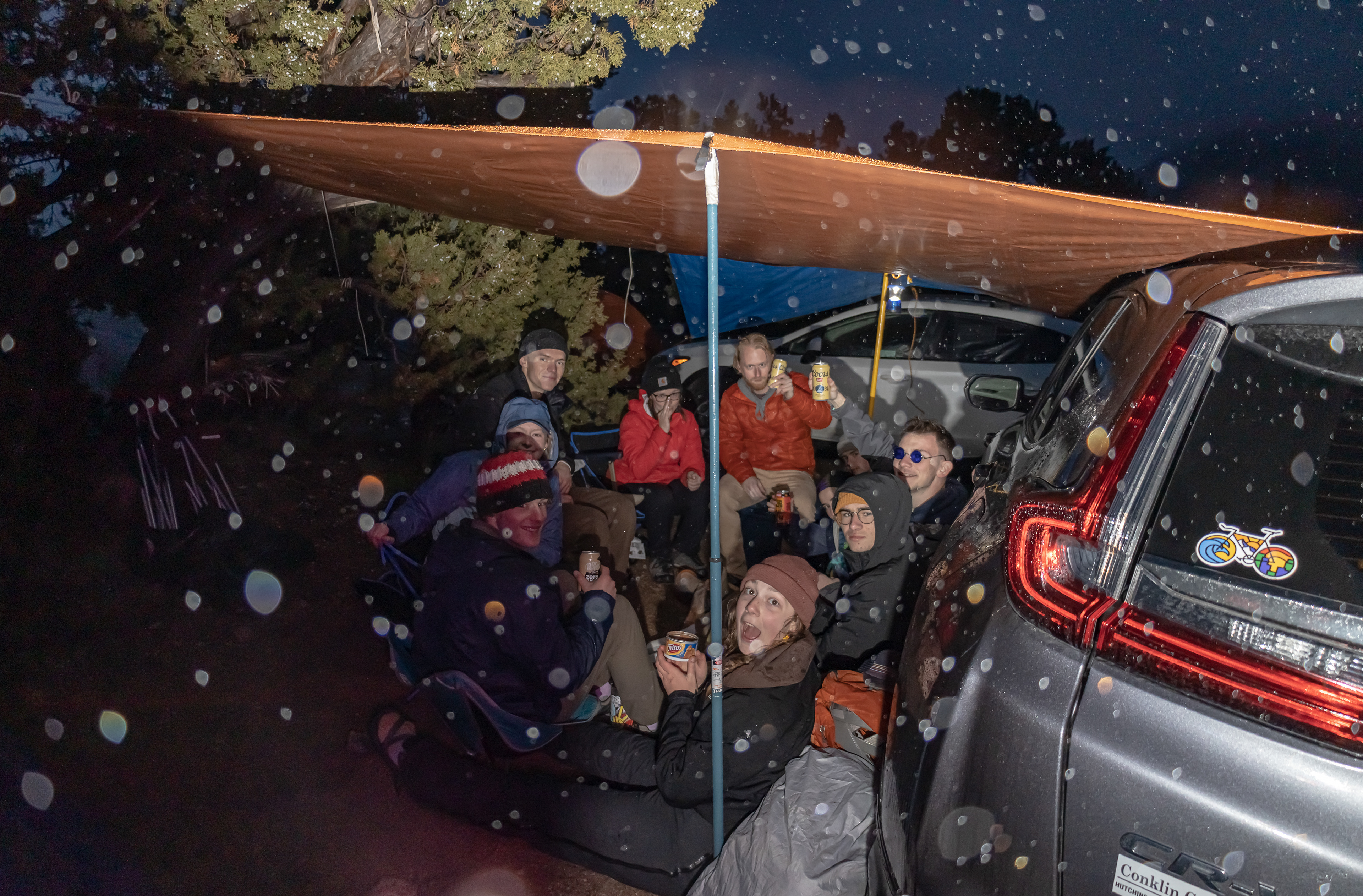 The University of Kansas Rock Climbing Club seeks shelter from the storm under an improvised car-tarp-structure at Lovell Canyon Campground in Mountain Springs, Nev. on March 12, 2023.