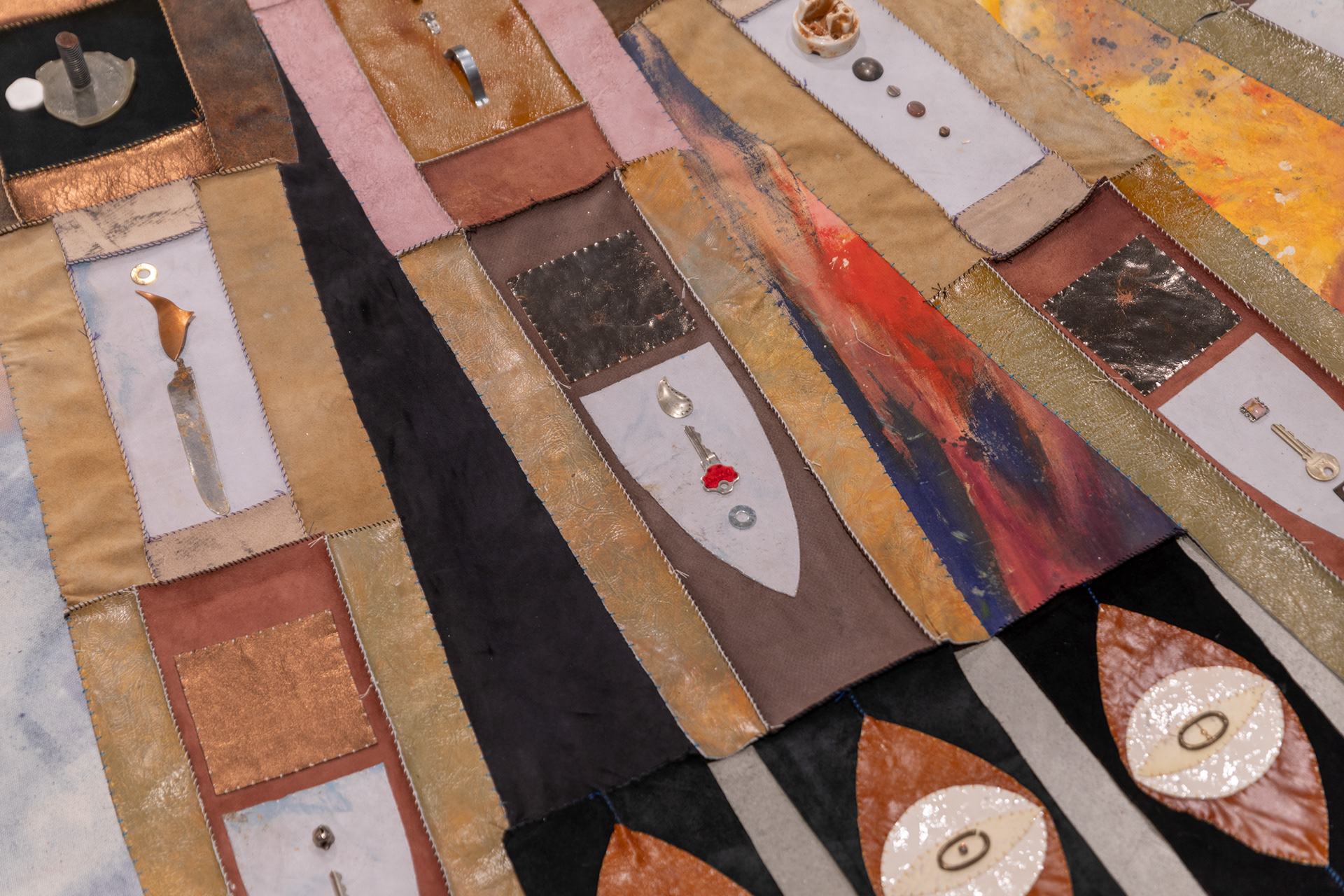 (detail) The Last Transmission, 2024, Repurposed leather and suede; cotton canvas; acrylic paint and finisher; leather, fabric, and natural dyes; assorted found metal, wood, ceramic, and glass objects; wire; beads; seashells; coated nylon thread; and coated cotton thread, 8H x 182 inch diameter