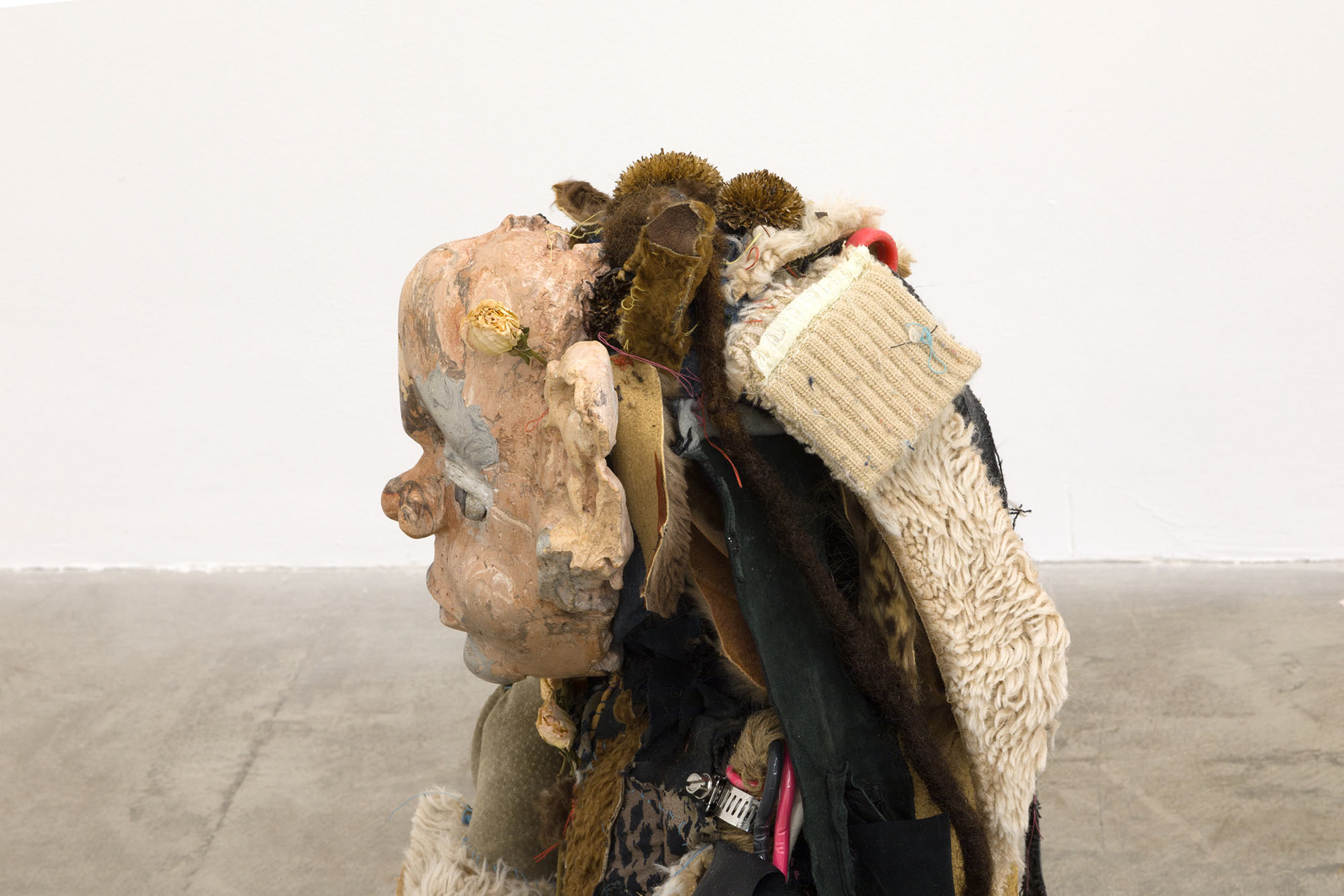 Boom bang (shiny girl). 2018. Hand sewn fabrics, furs and leathers, hand carved plaster, acrylic paint, wire, stones, jute, hardware, human hair, found toy, leather gloves, wood sculpture, chain, dried flowers. 20 x 16 x 20 in (50.8 x 40.6 x 50.8 cm).