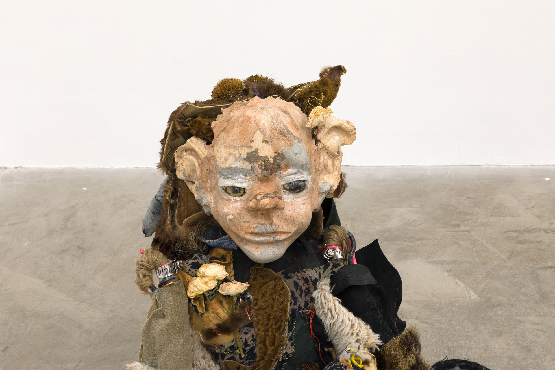 Boom bang (shiny girl). 2018. Hand sewn fabrics, furs and leathers, hand carved plaster, acrylic paint, wire, stones, jute, hardware, human hair, found toy, leather gloves, wood sculpture, chain, dried flowers. 20 x 16 x 20 in (50.8 x 40.6 x 50.8 cm).