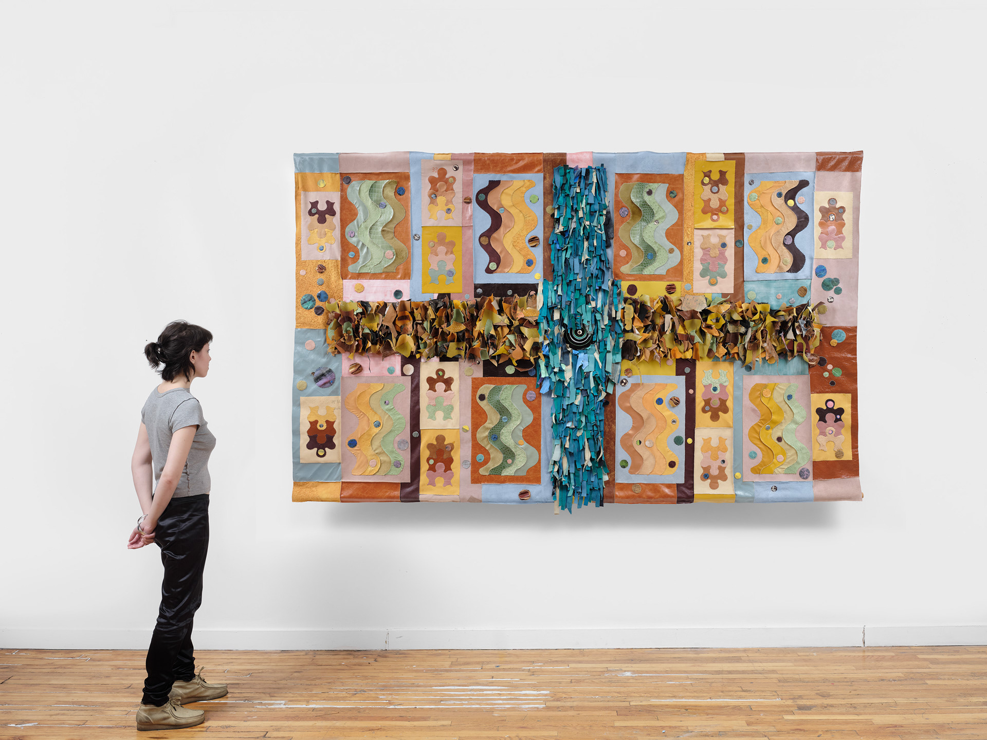 Return of the Martian Water God, 2022 Repurposed leather, vinyl, suede, acrylic paint, leather primer, PVA glue, leather cement, cattle bone bead, dutch trading bead, wooden dowel, steel bracket. 68 inches x 110 inches x 10 inches.