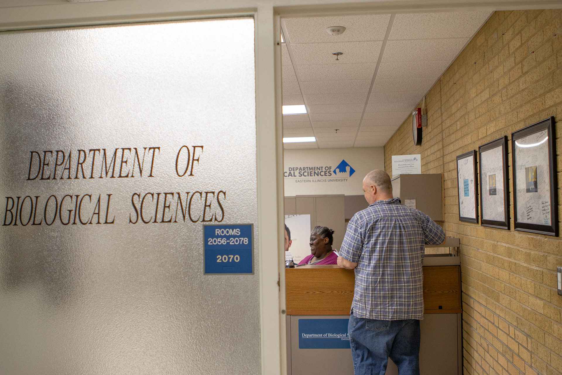 Marschelle McCoy, the office manager in the biology department, talks with professor Robert Colombo at her desk on Thursday afternoon in the Biological Sciences Building on Feb. 22.
