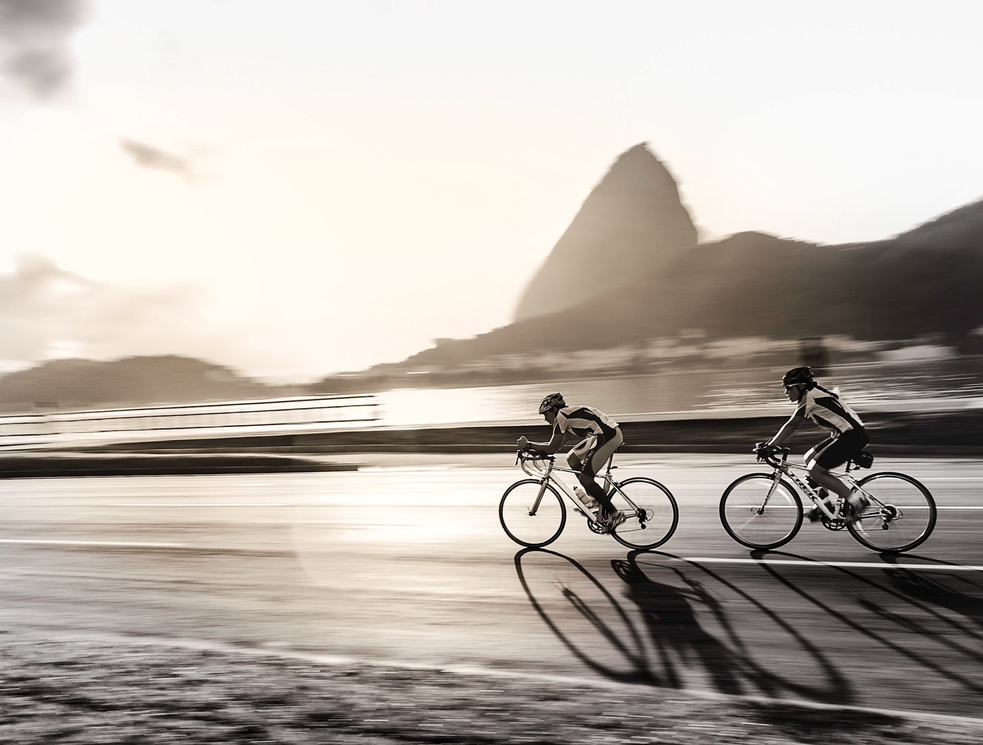 Sob o nascer do sol, na luz da manhã, ciclistas praticam velocidade no aterro do flamengo, Rio de Janeiro.