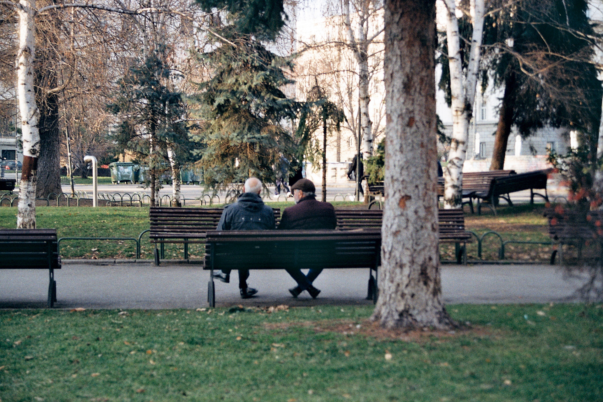 Men sat on a bench in the park outside the National Theatre