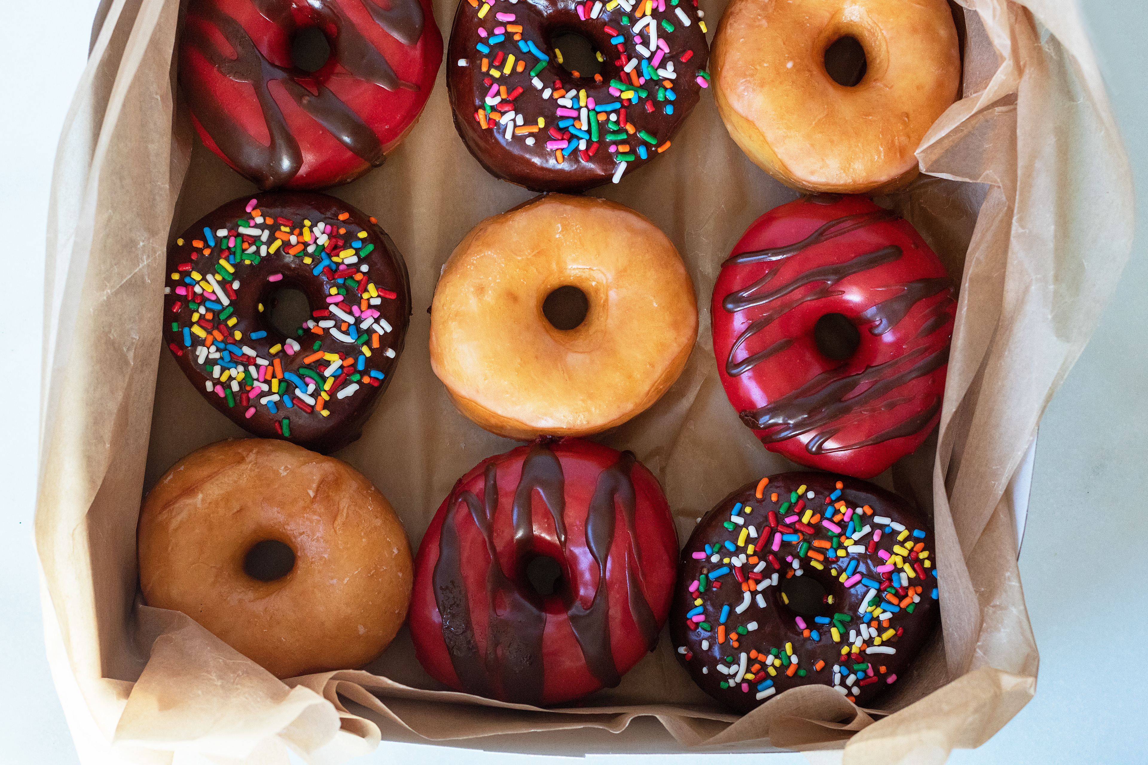 box of glazed, chocolate sprinkle, and raspberry chocolate glazed doughnuts