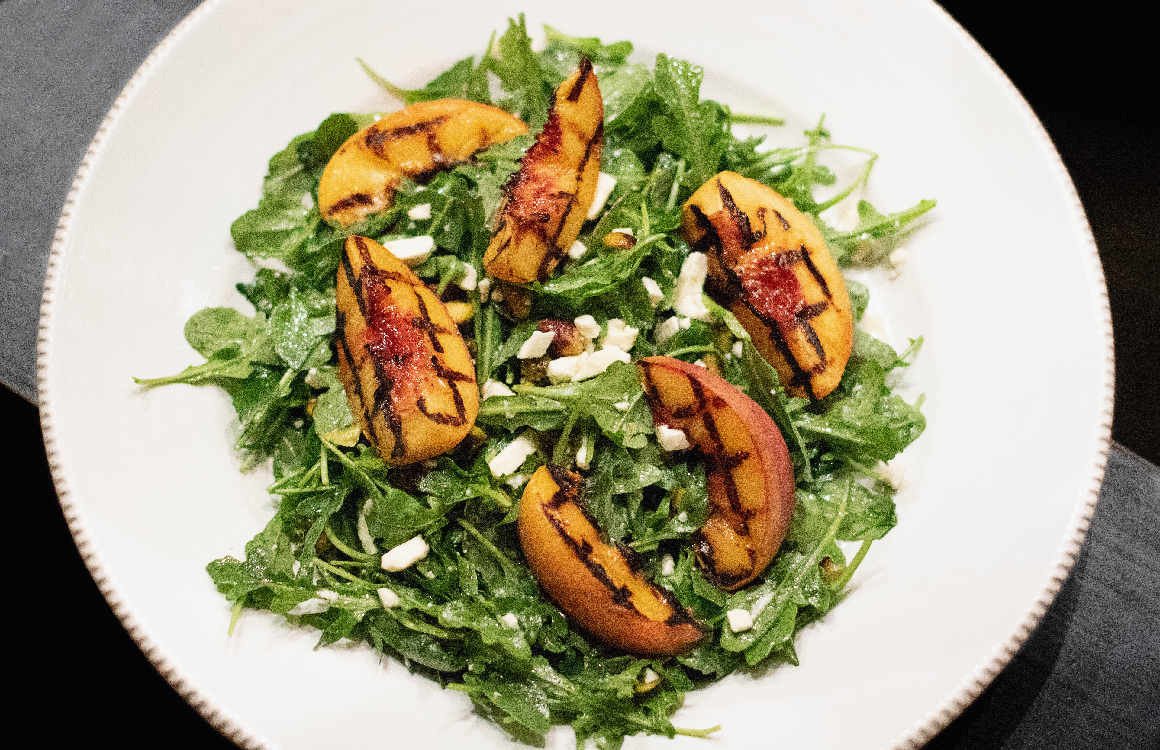 grilled peach salad with feta and pistachios on arugula