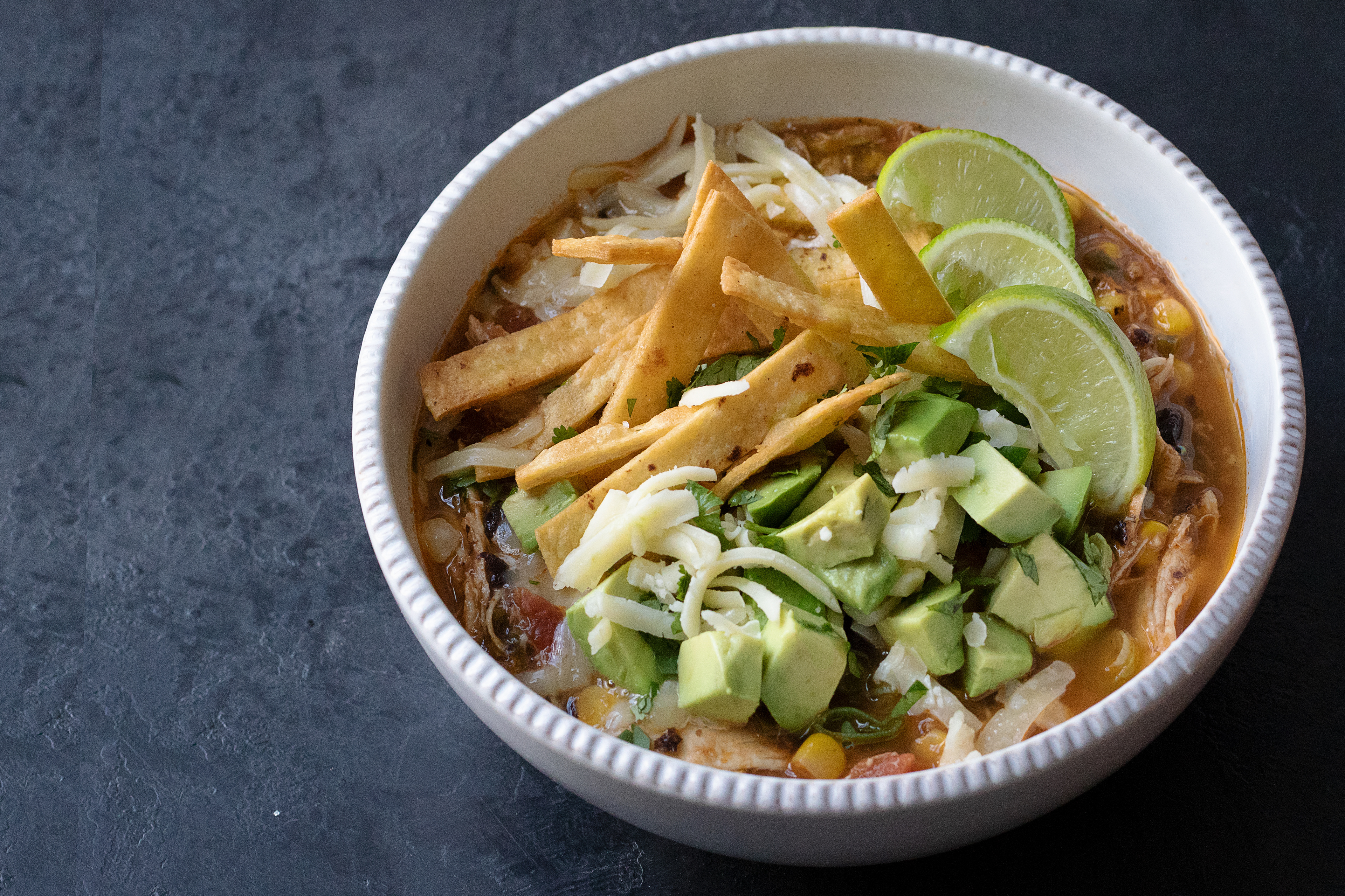 tortilla soup topped with diced avocados, scallions, montery jack, and fresh lime juice