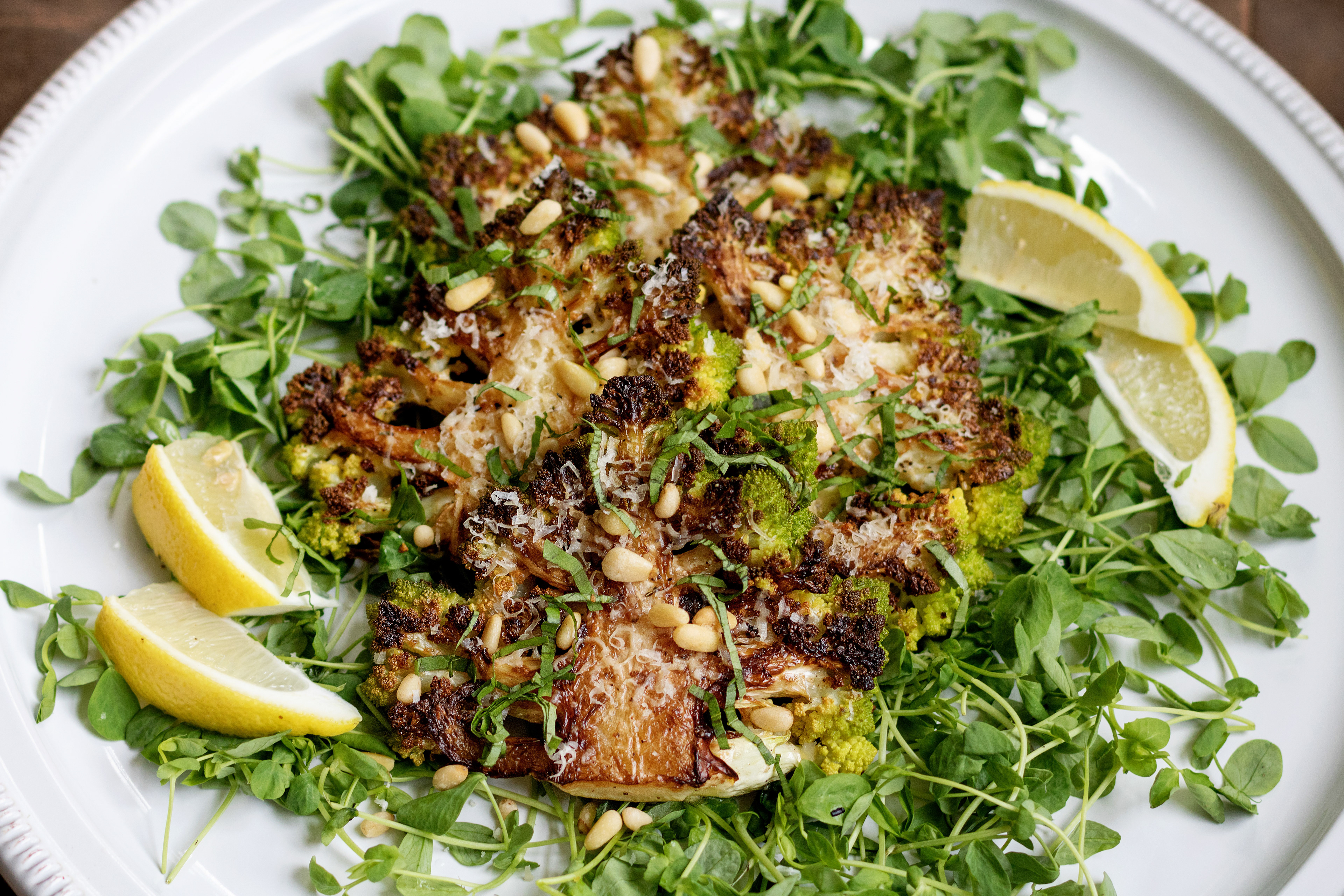 roasted romanesco broccoli steaks with a squeeze of lemon, grated parmesan, toasted pine nuts, and basil