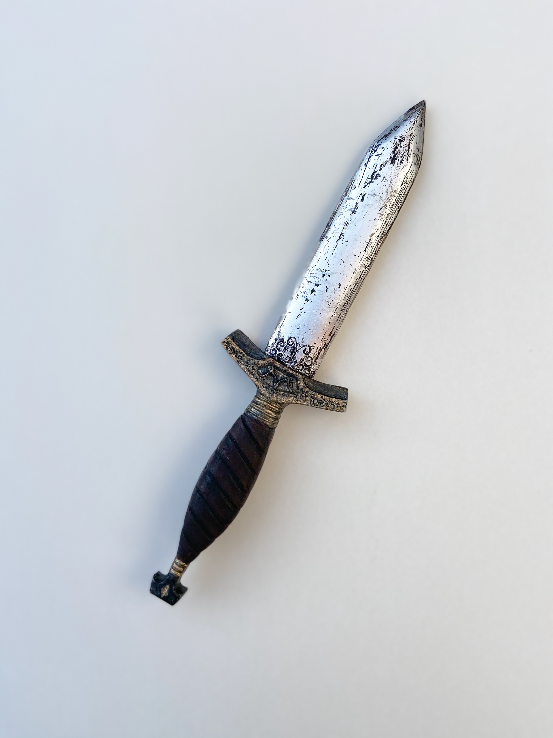 Dagger handle sculpted from Plastiline and cast from Polyurethane fast cast resin before painted with Acrylic paints.  Blade was made from Balsa wood and covered with insulation tape with a black wash to highlight wear effects.