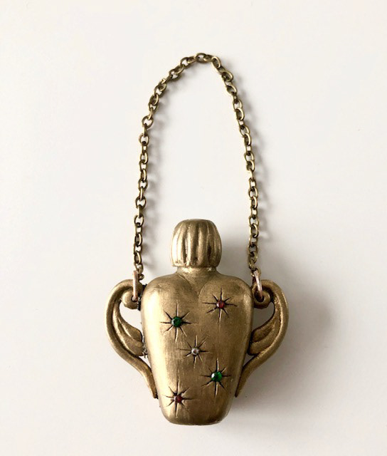 Chatelaine scent bottle first sculpted from Plastiline before being moulded in silicone and cast from laminating resin with brass powder added.  Swarovski crystals were set in place and a chain added.   Bottle measures approx. 5cm and has a working screw-top lid.